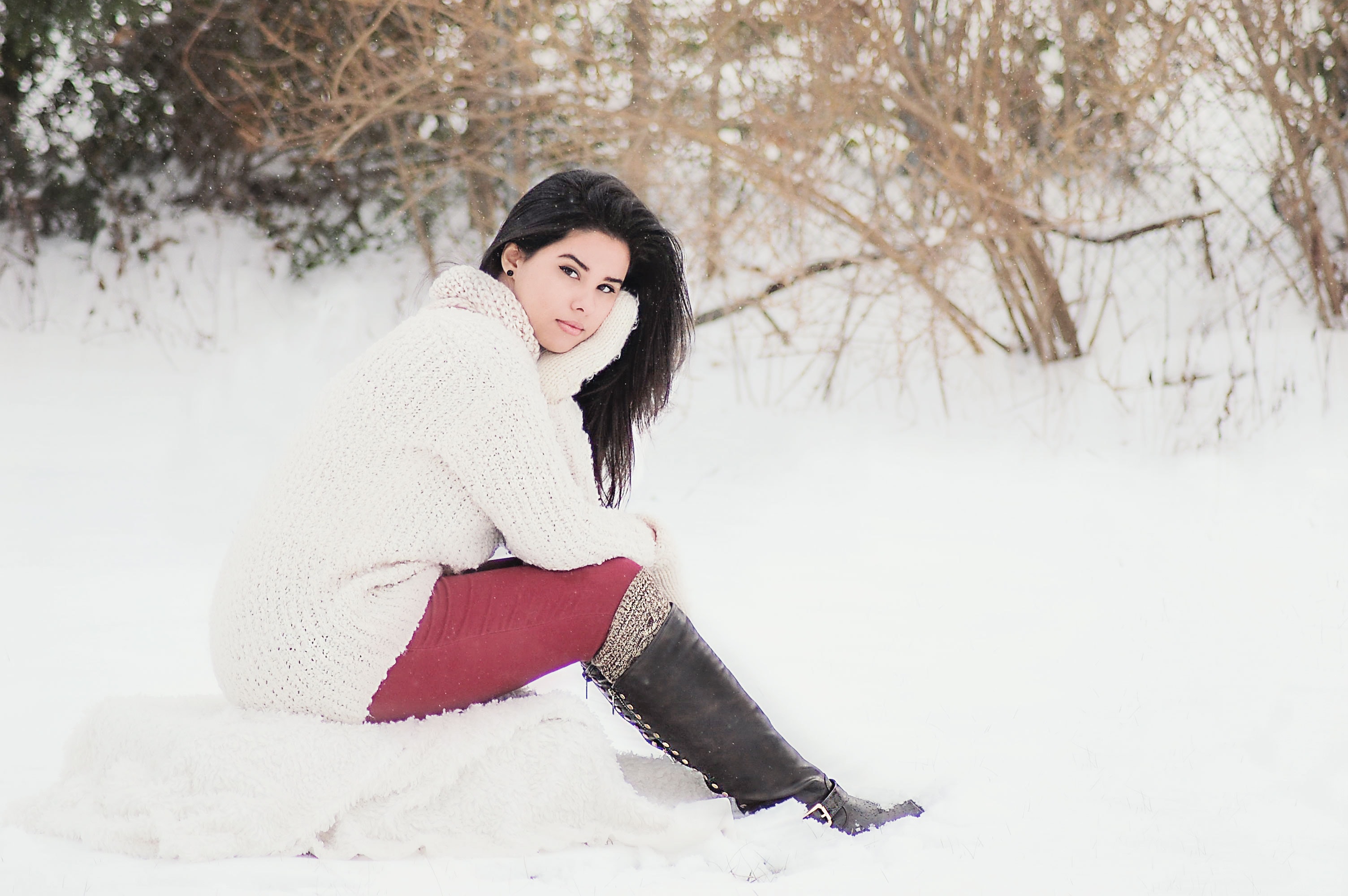 Woman in white sweater sitting near grass during winter season photo