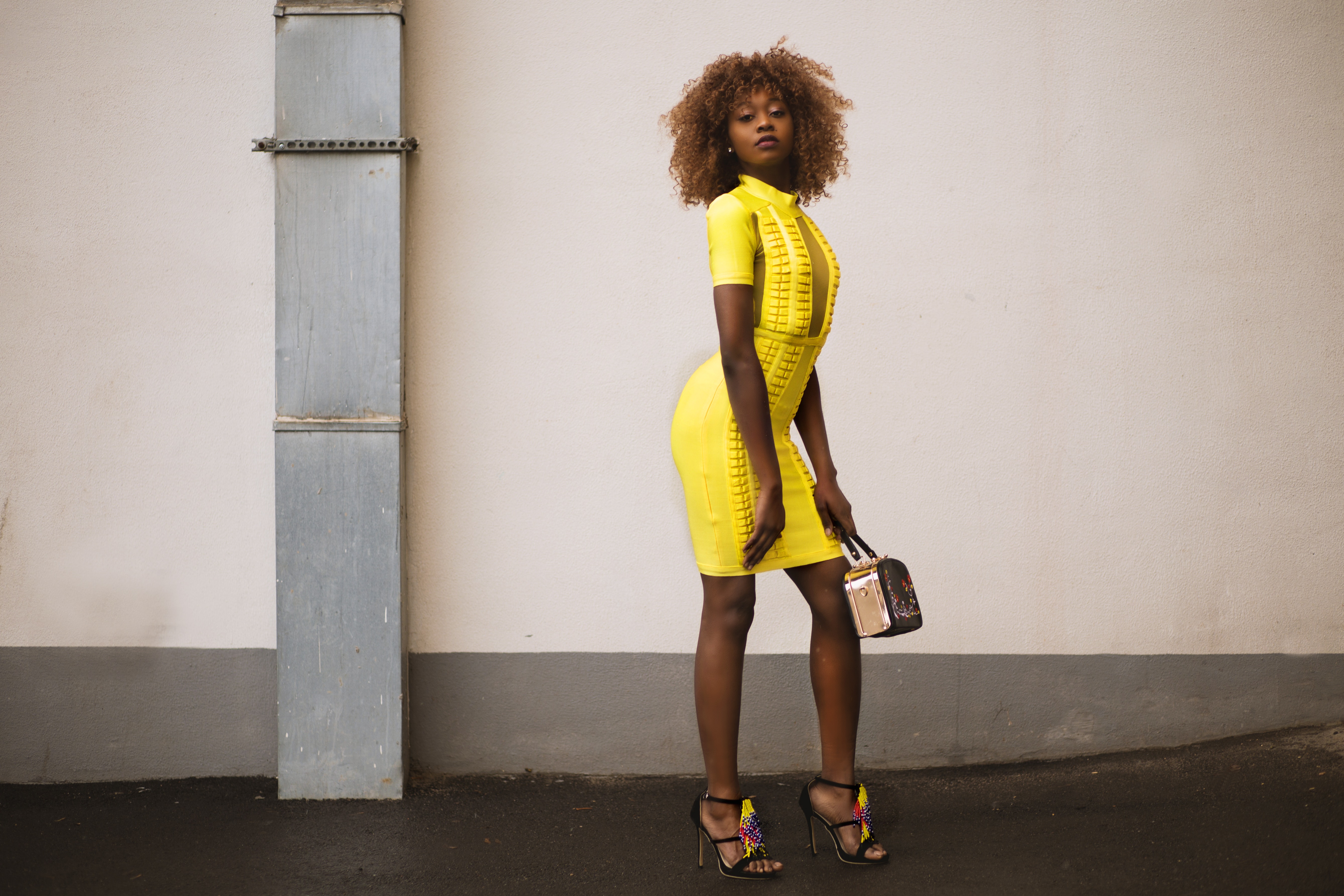 Woman in yellow knitted dress holding beige handbag photo