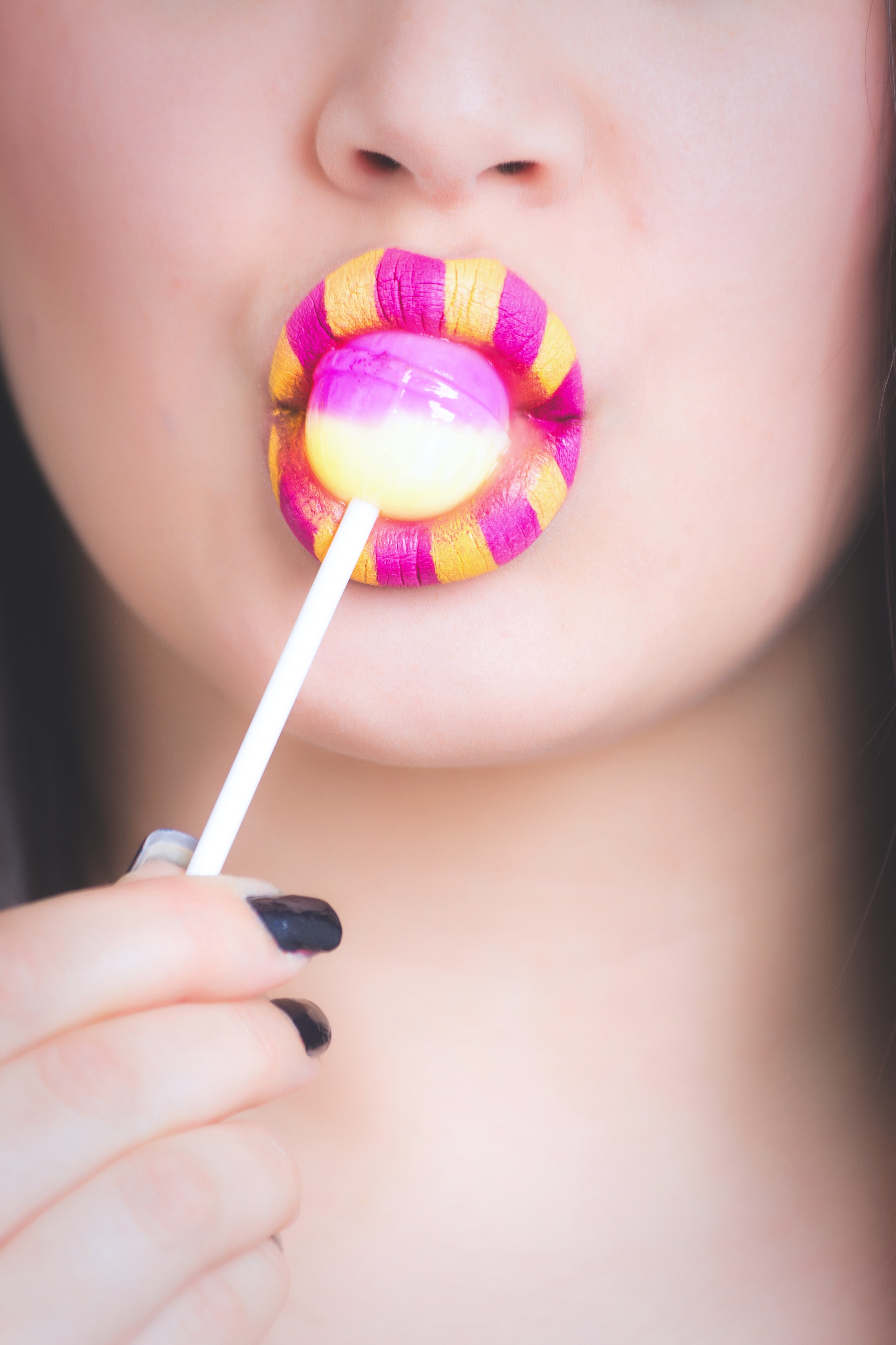 Woman licking pink and white lollipop photo