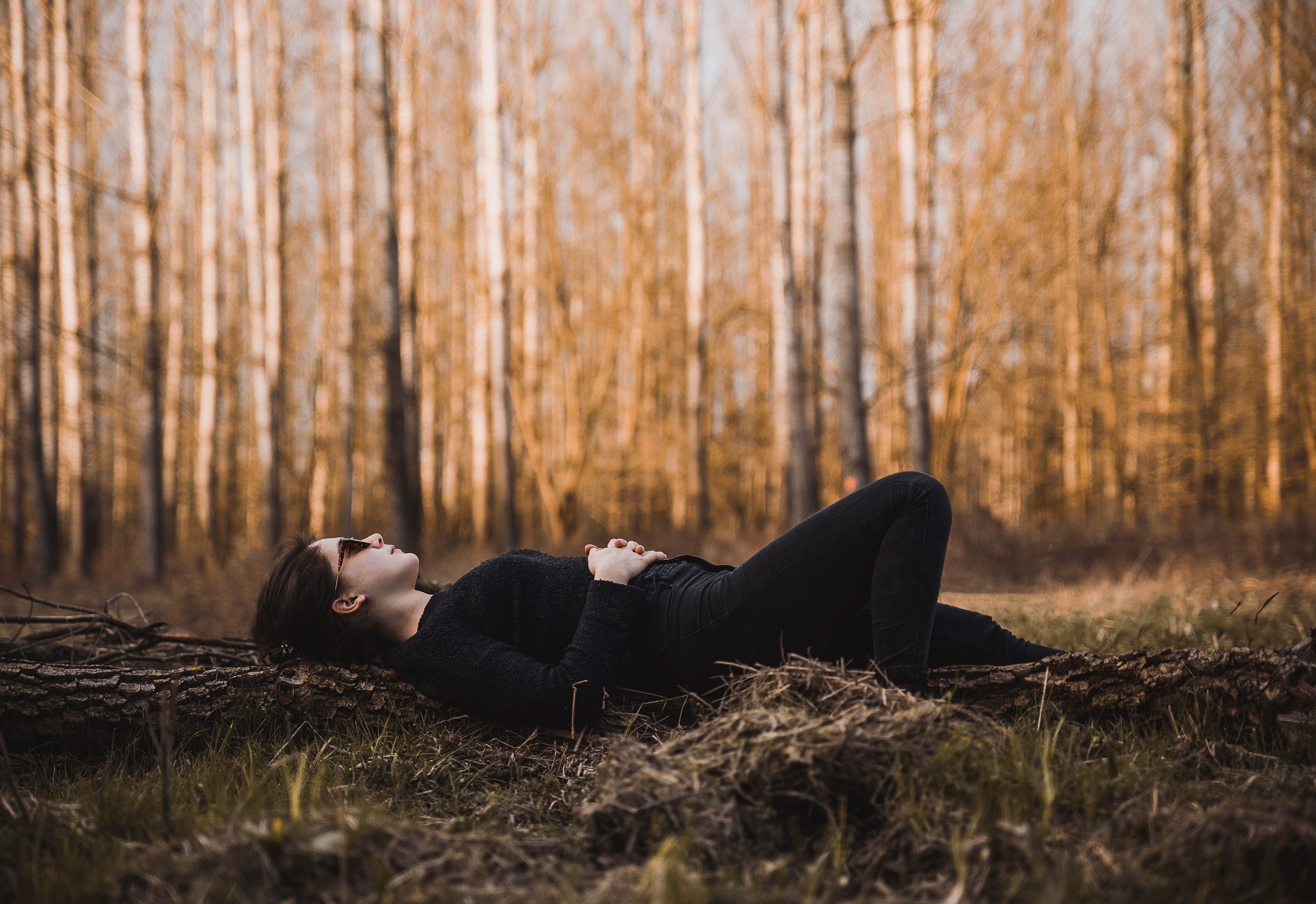 Woman lying on the ground surrounded by bare trees photo