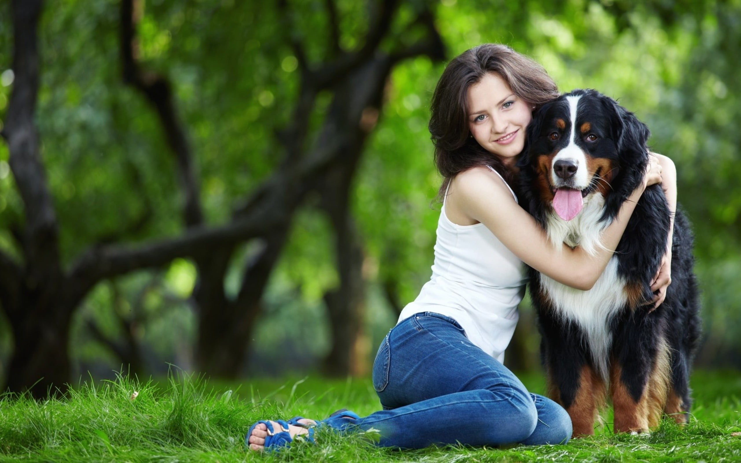 Woman wearing white tank top hugging dog on the grass during day ...
