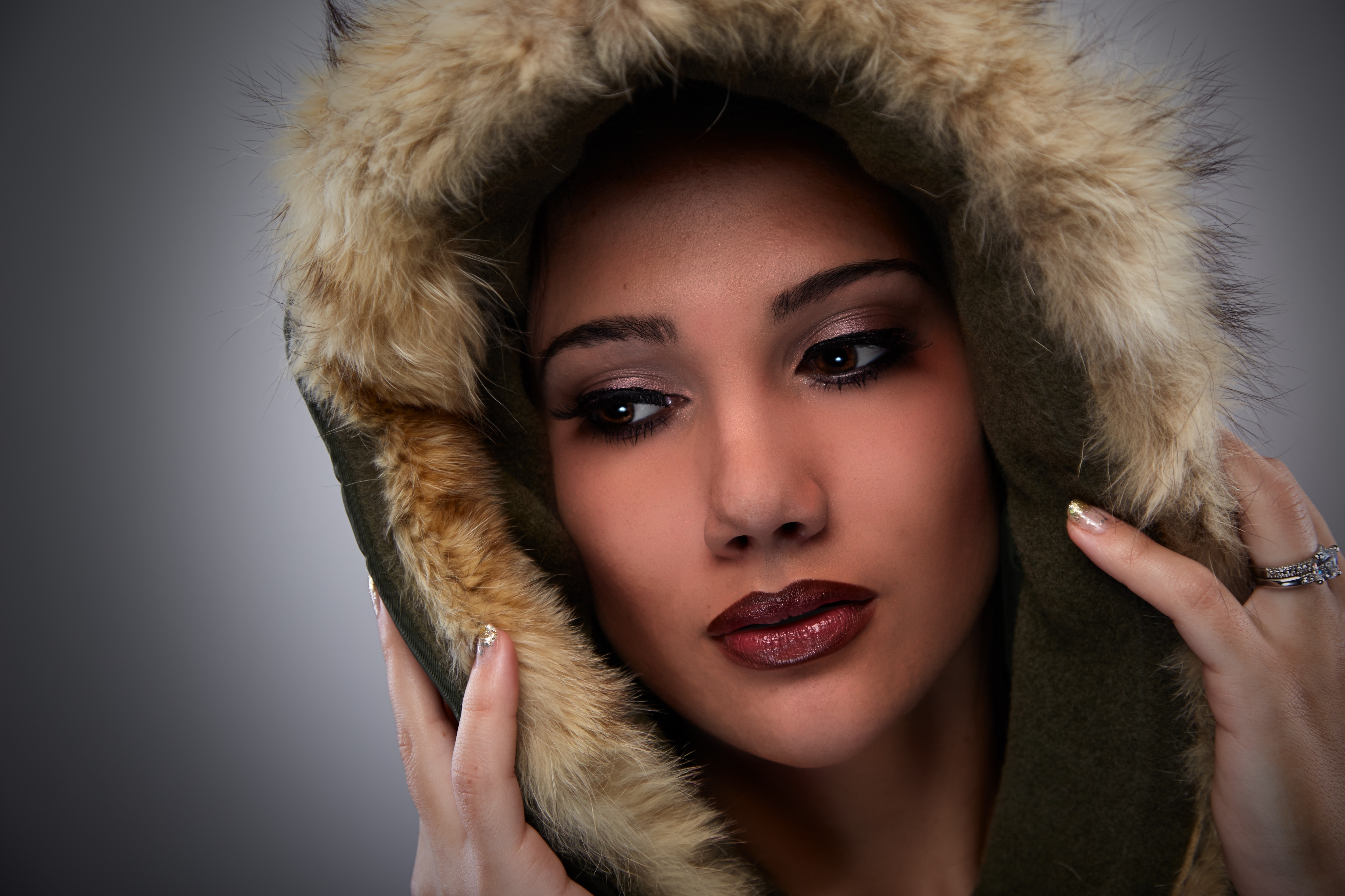 Woman on black mascara red lipstick cover her face with brown fur coat photo