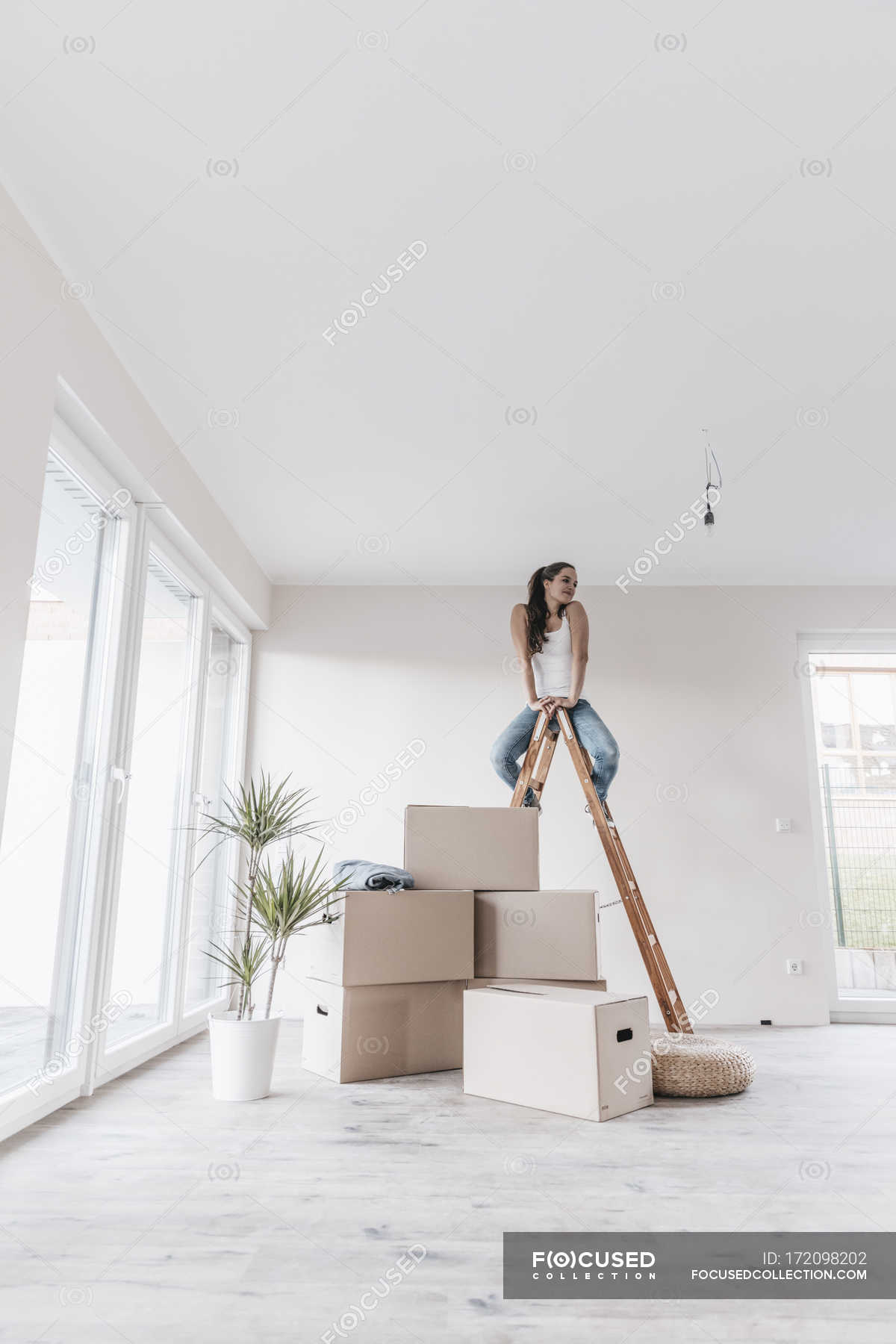Mature woman sitting on ladder in new home — Stock Photo | #172098202