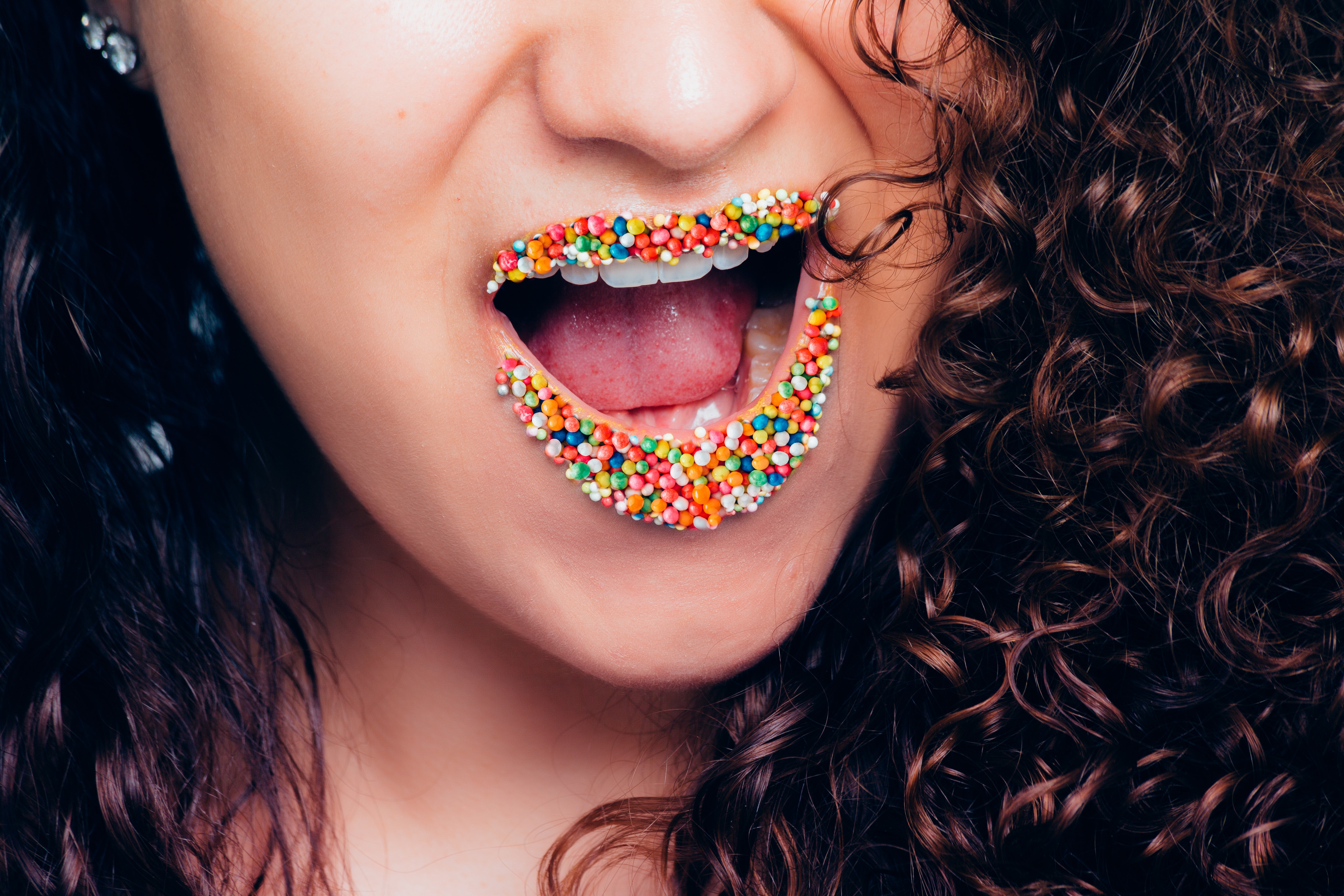 Woman opening her mouth with multicolored sweets photo