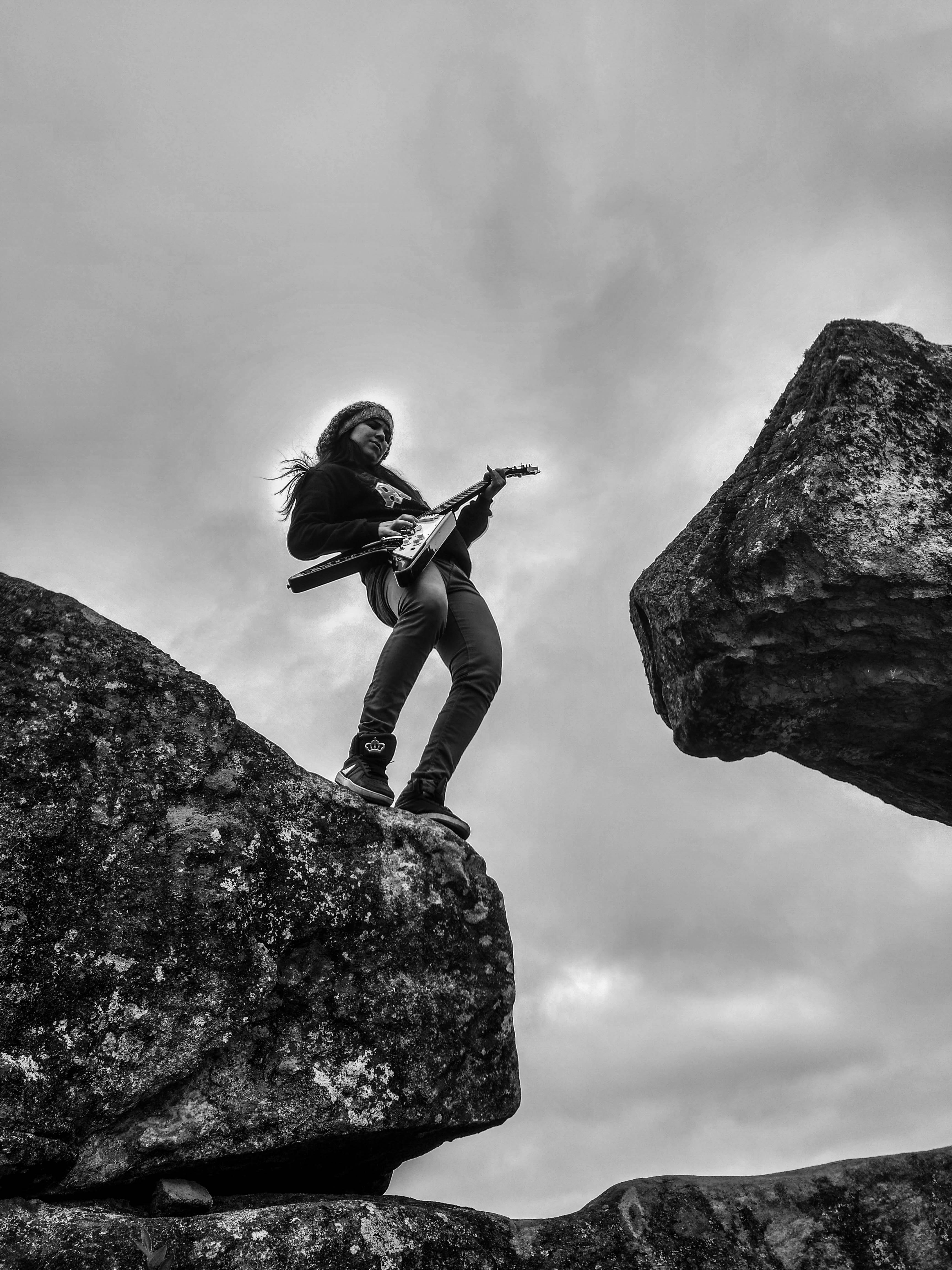 Woman playing electric guitar on top of rock formation photo