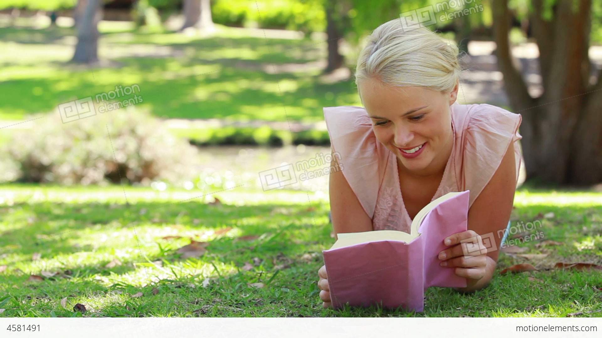 A Woman Reading A Book Lying In The Park As She Th Stock video ...
