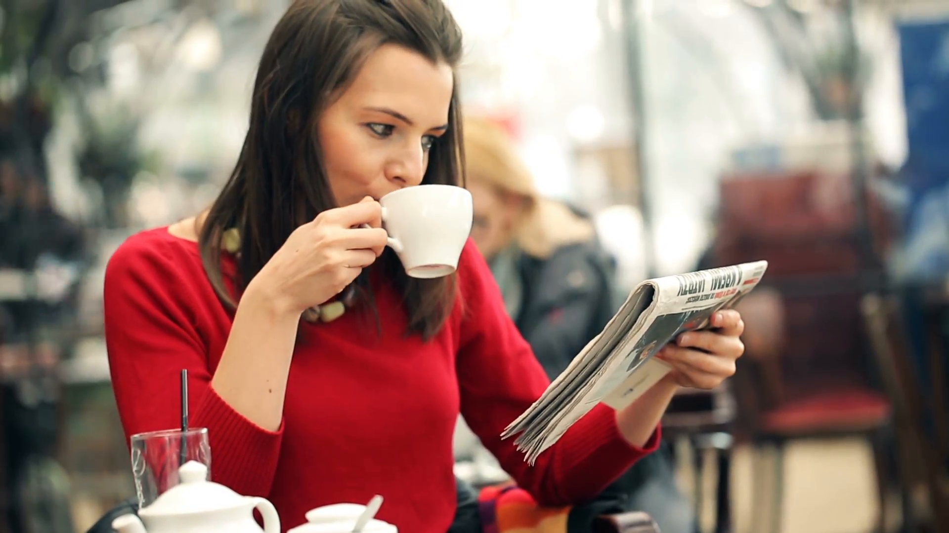 young beautiful woman reading newspaper and drinking tea in the cafe ...