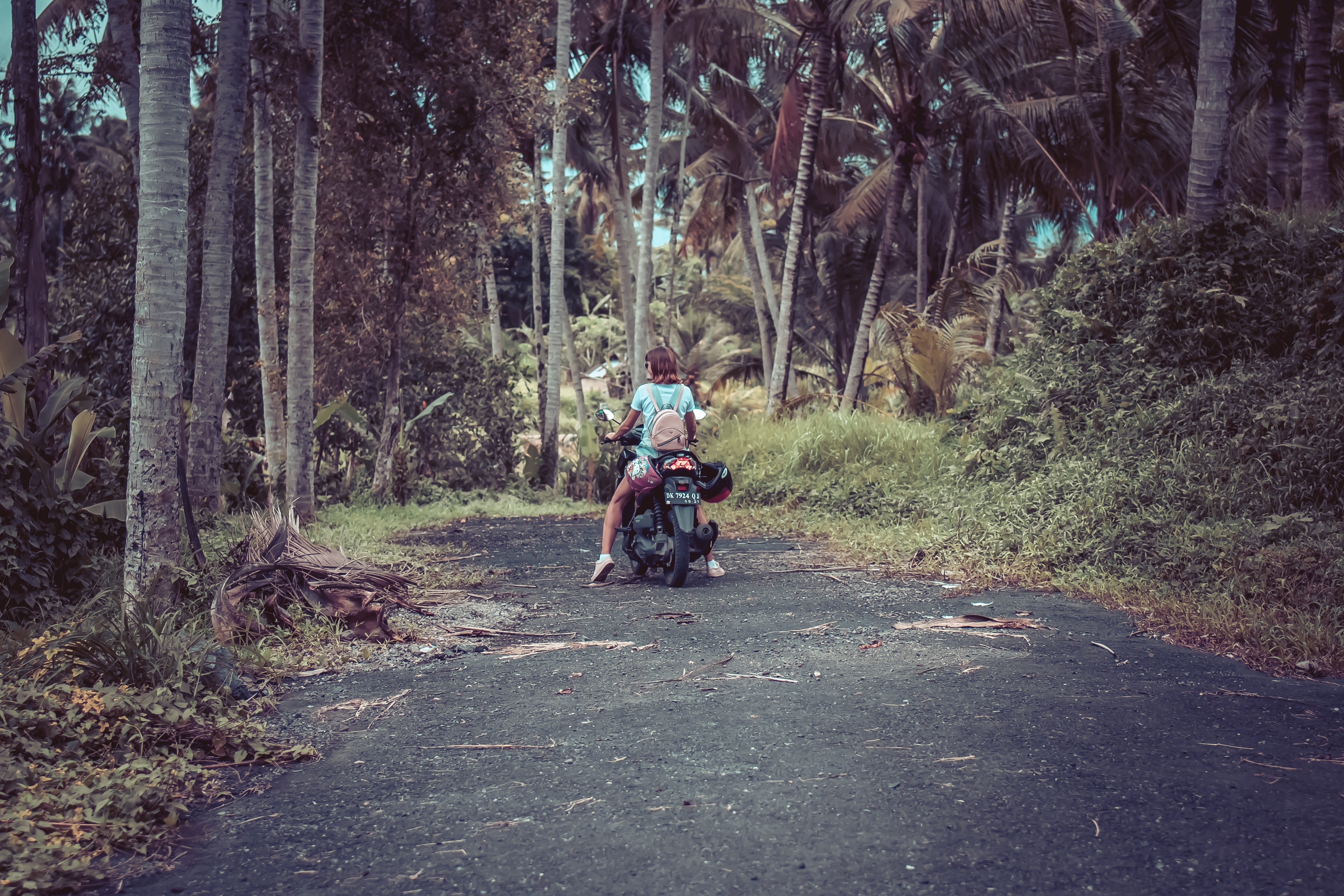 Woman riding motor scooter near coconut trees photo
