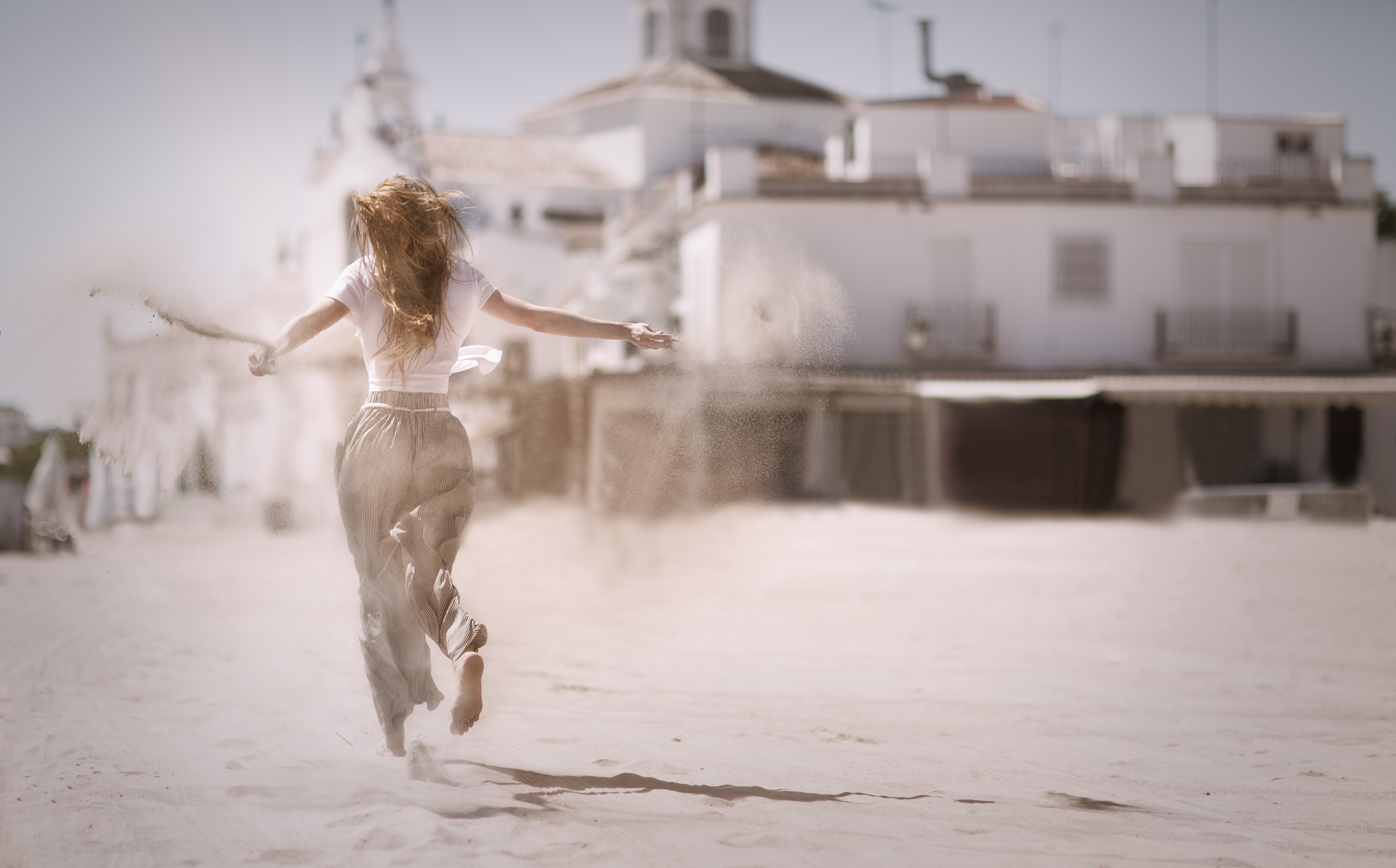 Woman running on sand near white concrete building photo