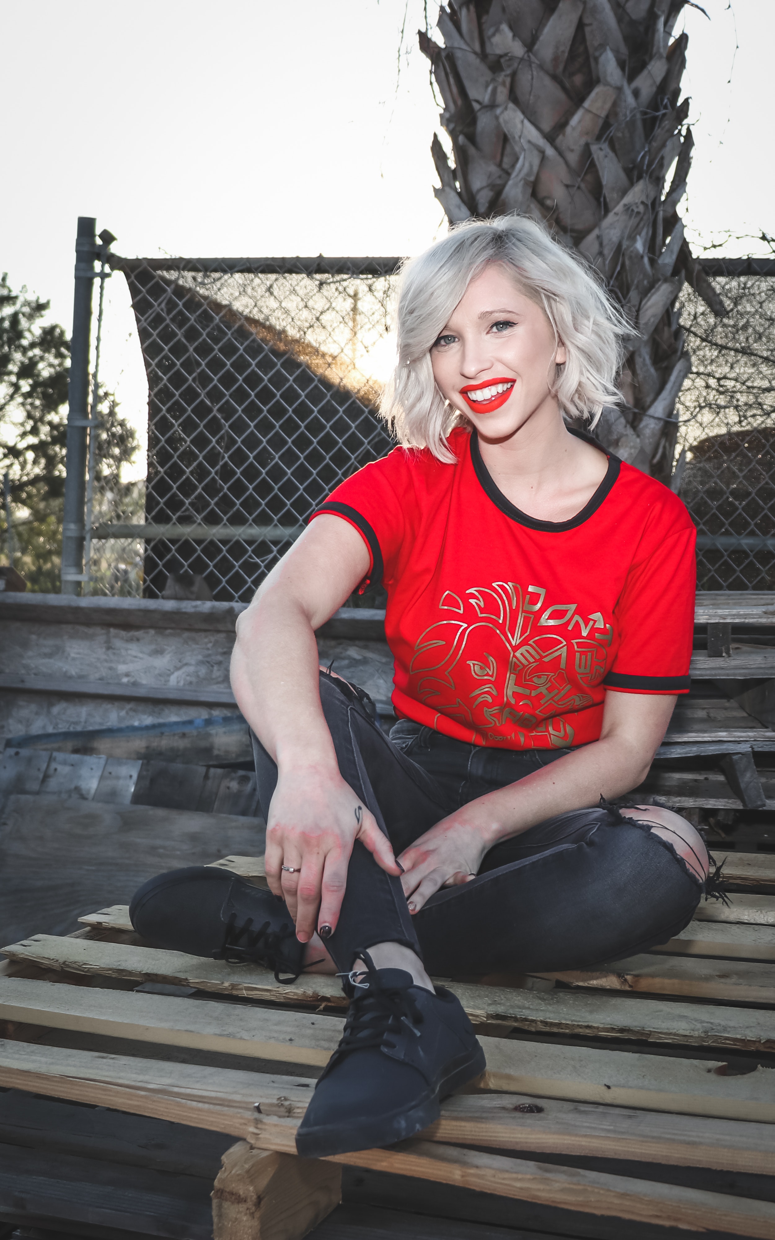 Woman sit on pallet wearing crew-neck t-shirt and distressed black fitted jeans photo