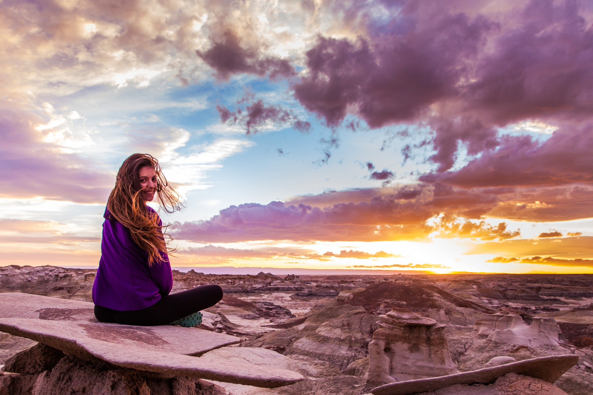 Woman sits on mountain under cloudy sky at sunset photo