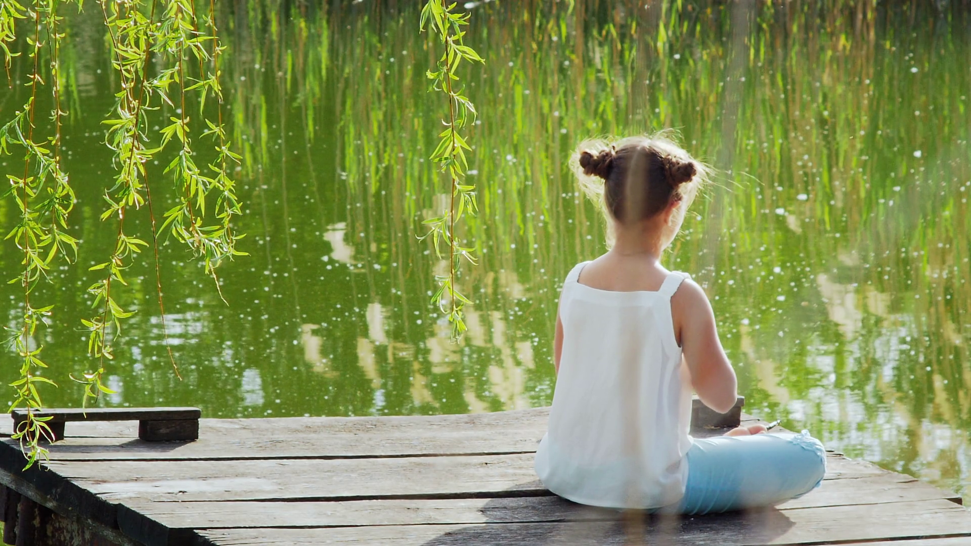 View from the back. Young girl relaxing meditating on the lake. Girl ...