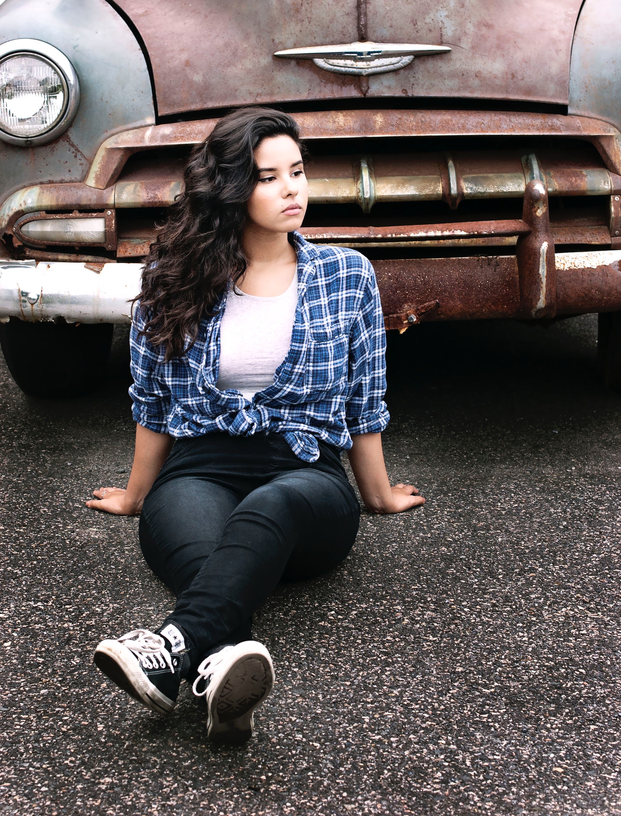 Woman sitting on gray pavement near vintage gray and brown car photo