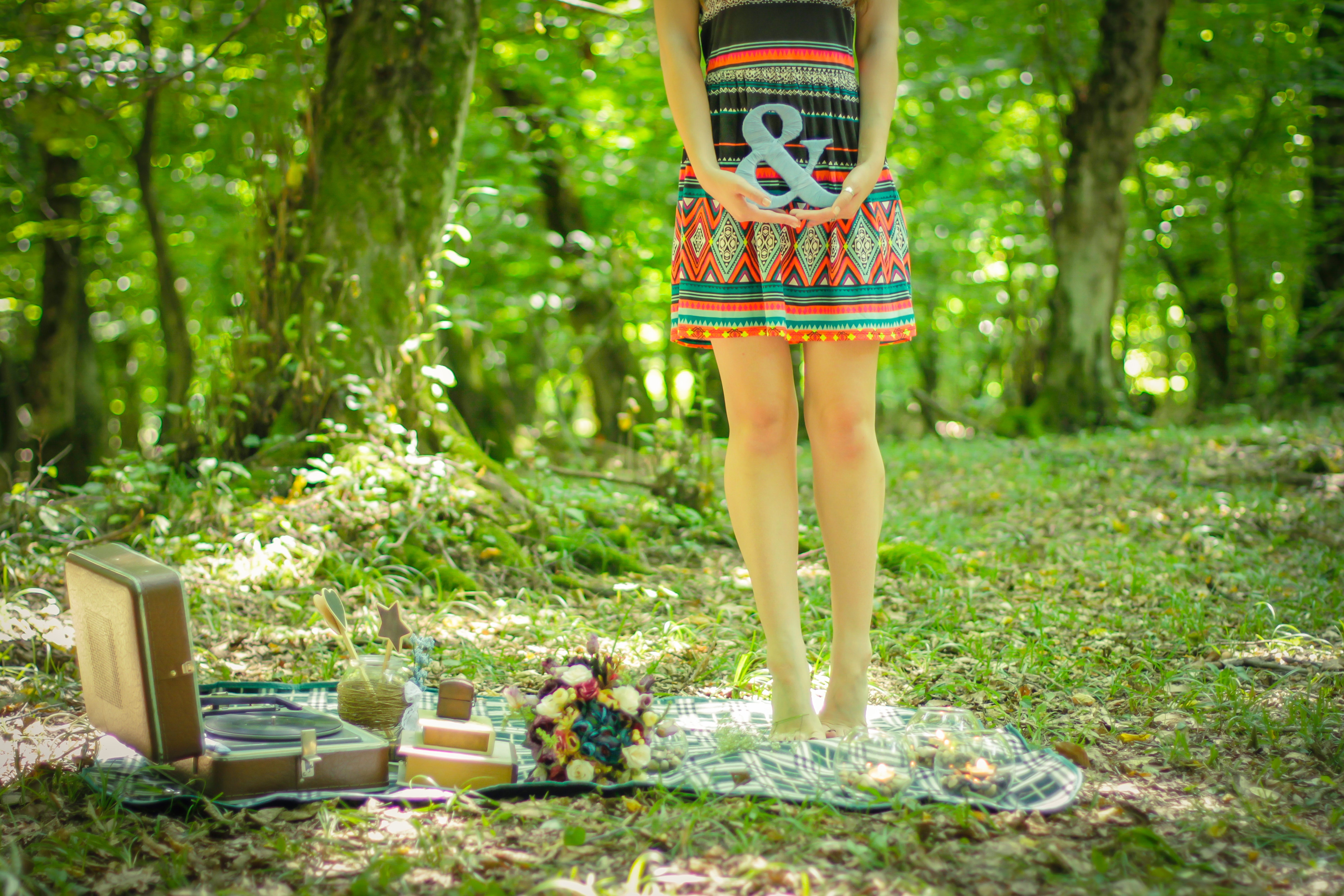 Woman standing on picnic mat holding ampersand lettering photo