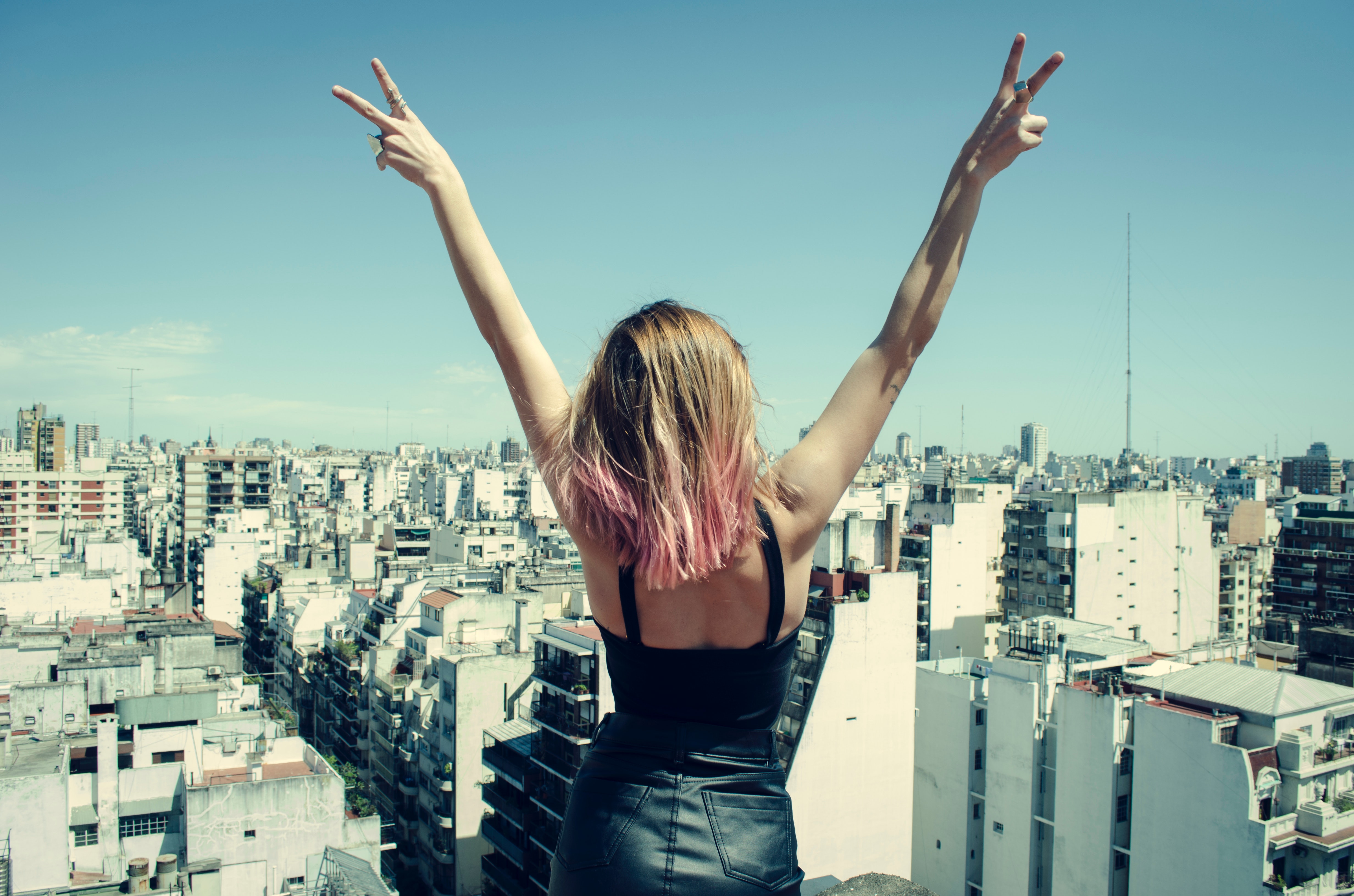 Woman standing on rooftop putting hands in the air under clear sky photo