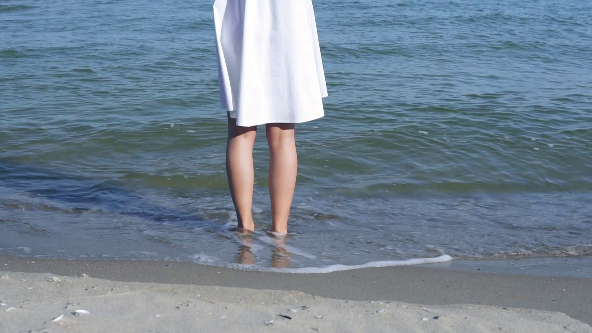 Woman standing on sand in water barefoot. Girl standing in shallow ...