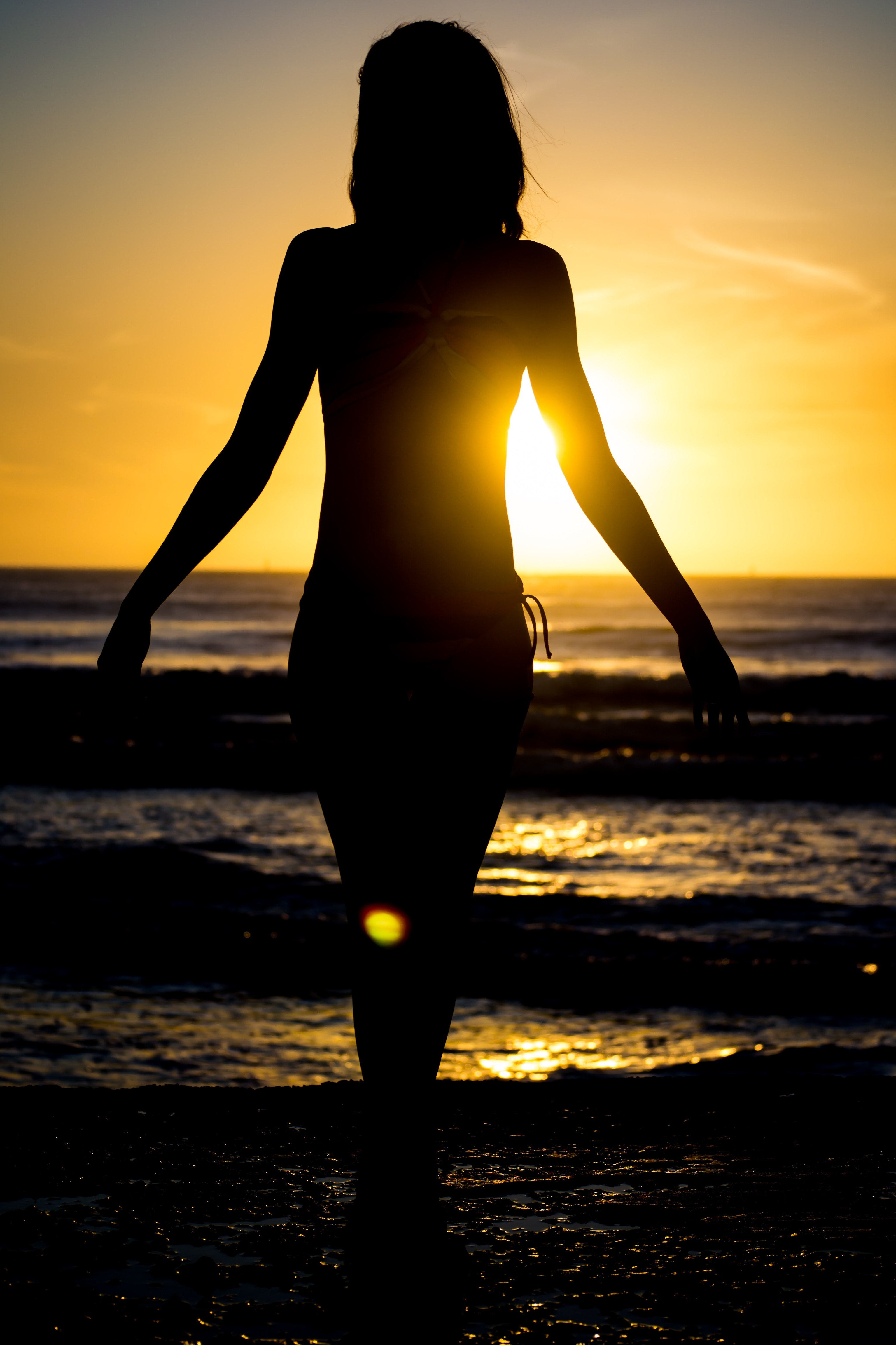 Woman Standing on Beach during Sunset