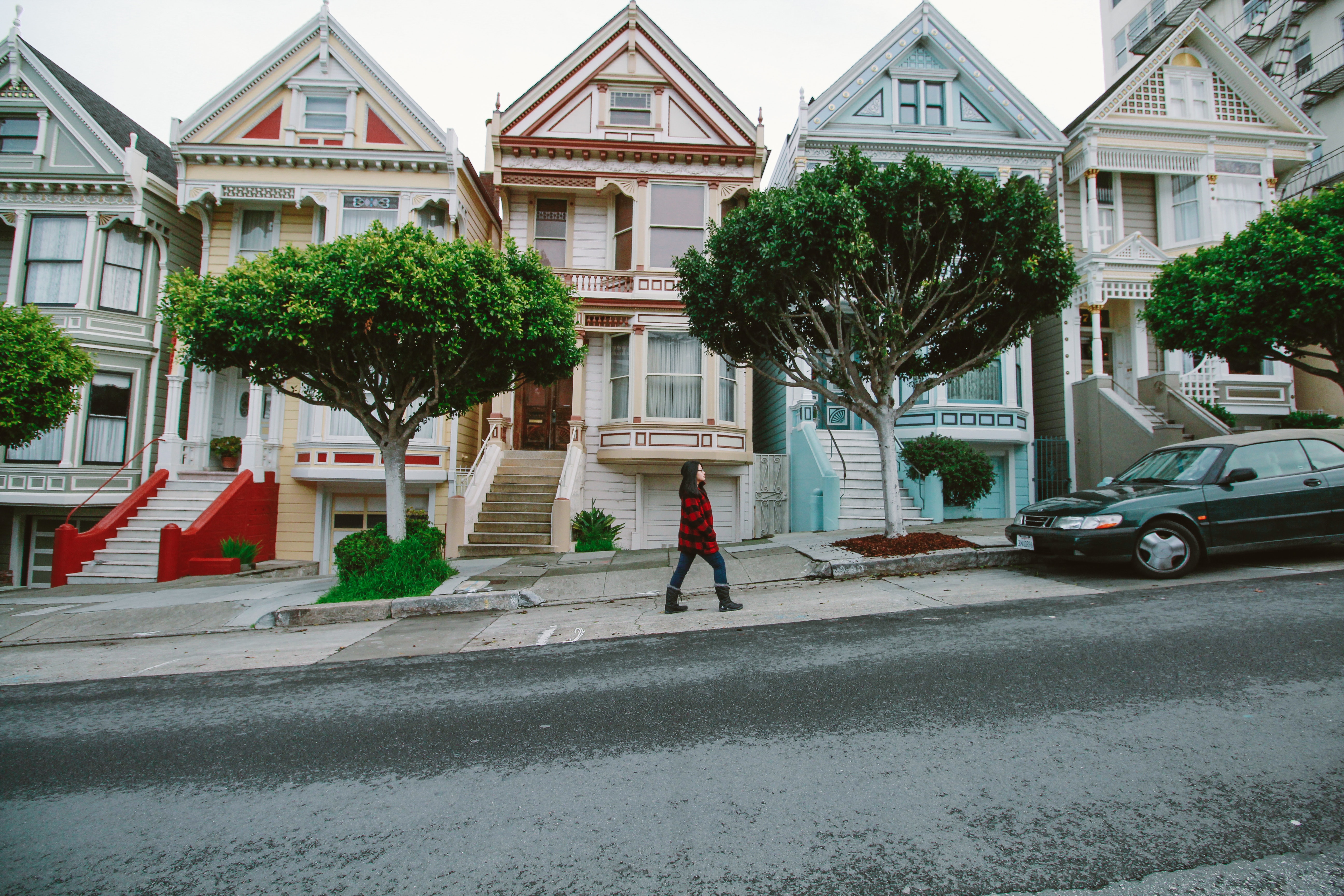 Woman walking toward black sedan parked in front of colorful houses photo