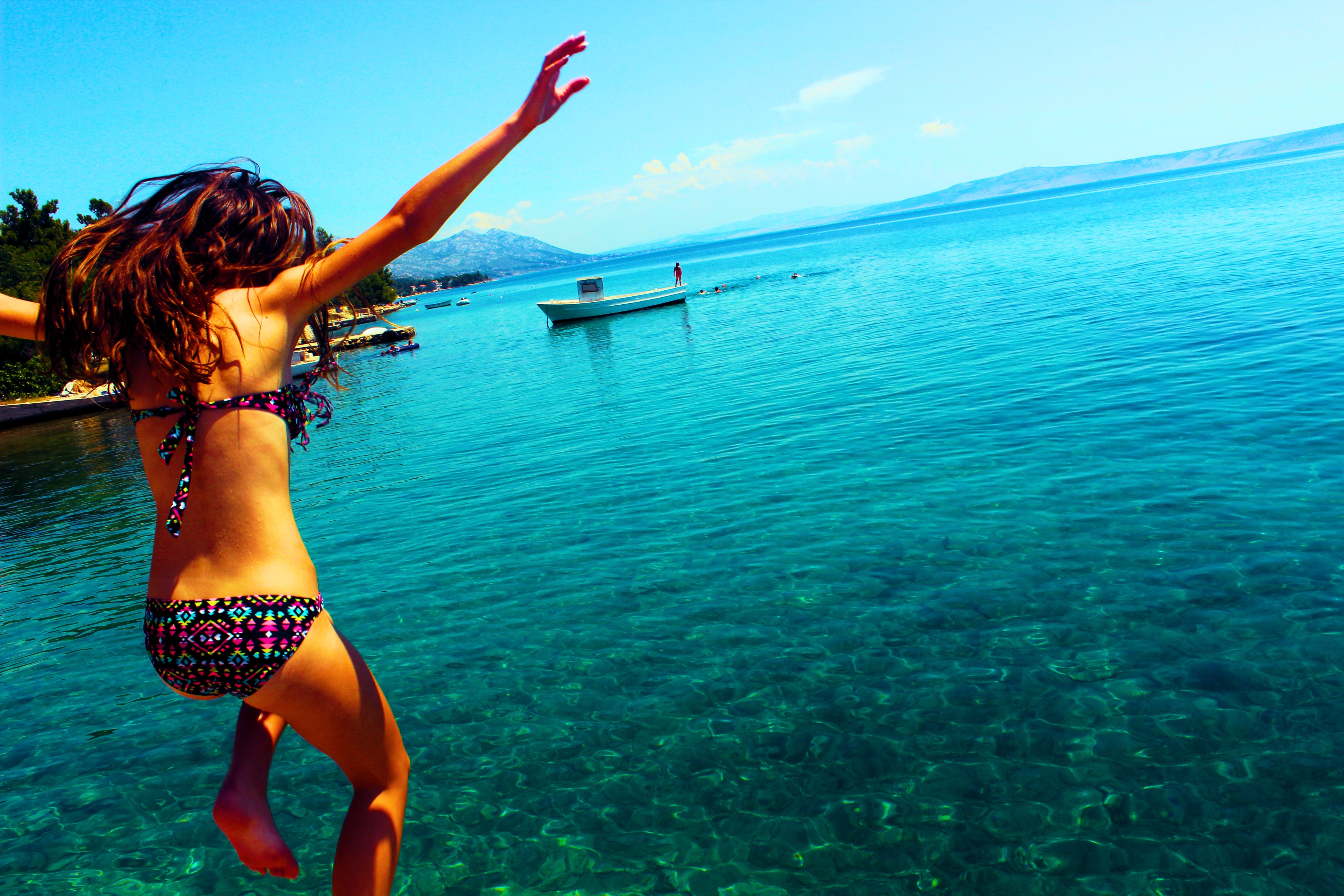 Woman wearing bikini jumping to the beach photo