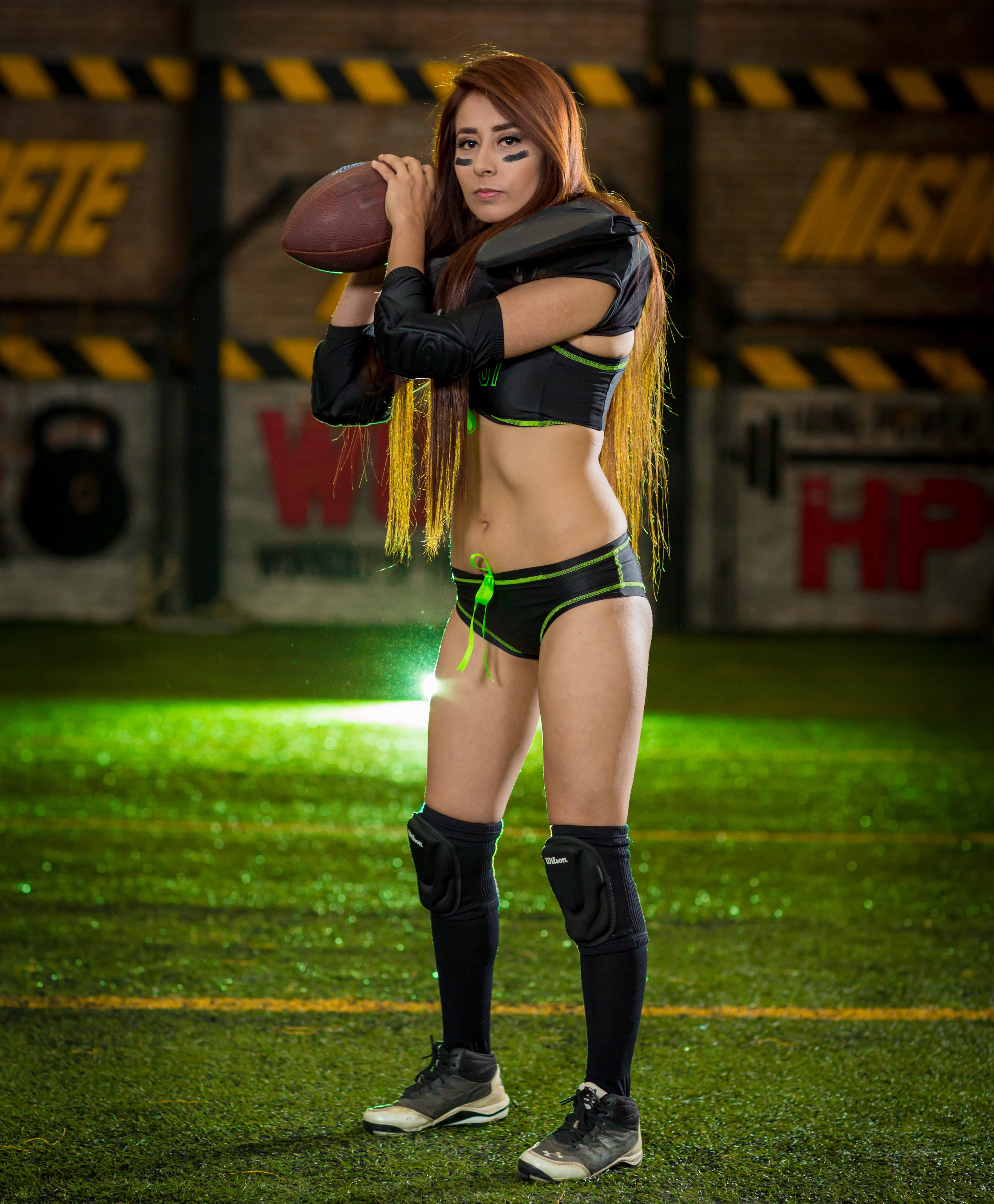 Woman wearing black-and-green sports bra and pantie holding rugby ball photo