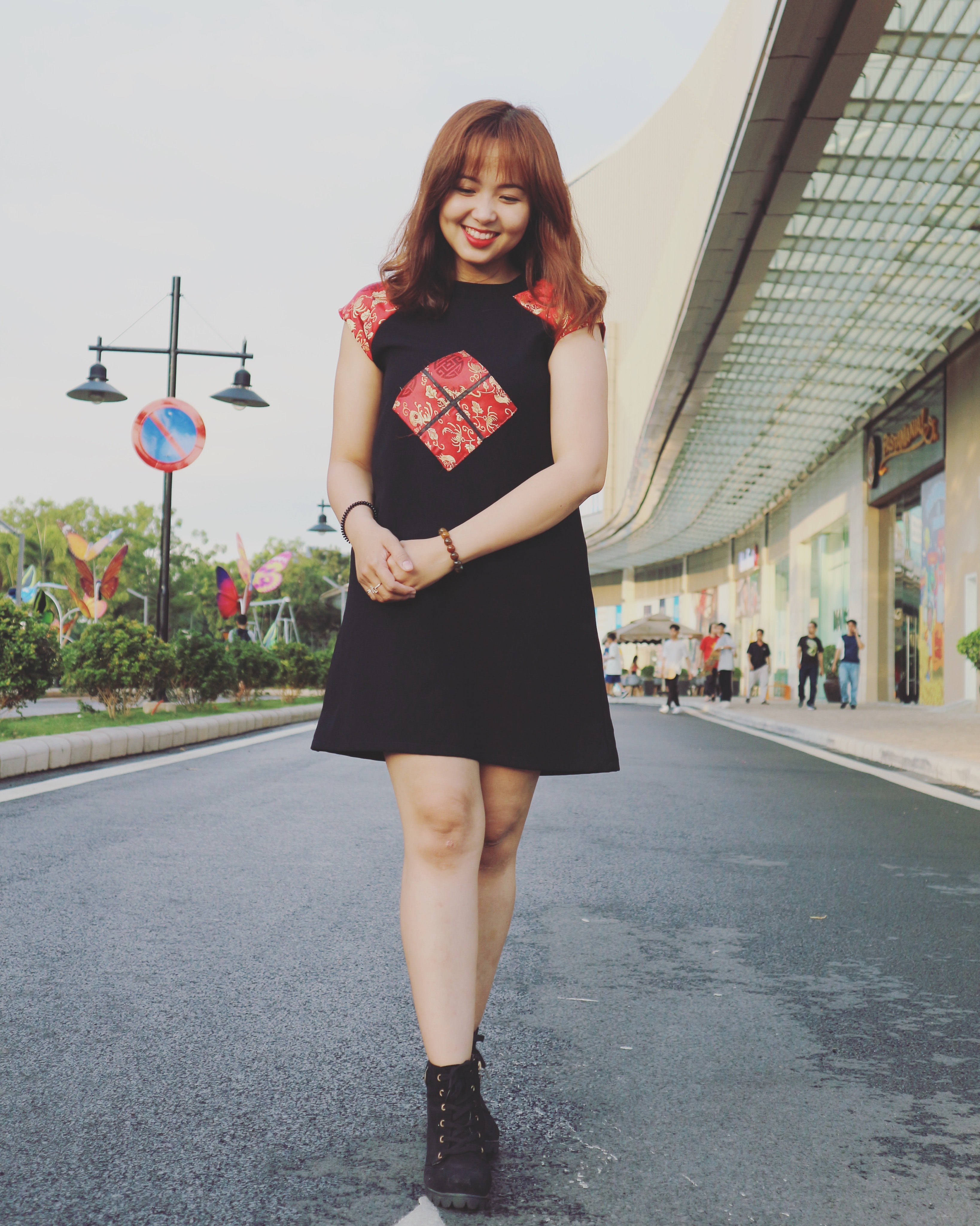 Woman wearing black and red cap-sleeved crew-neck dress and black high-top sneakers photo