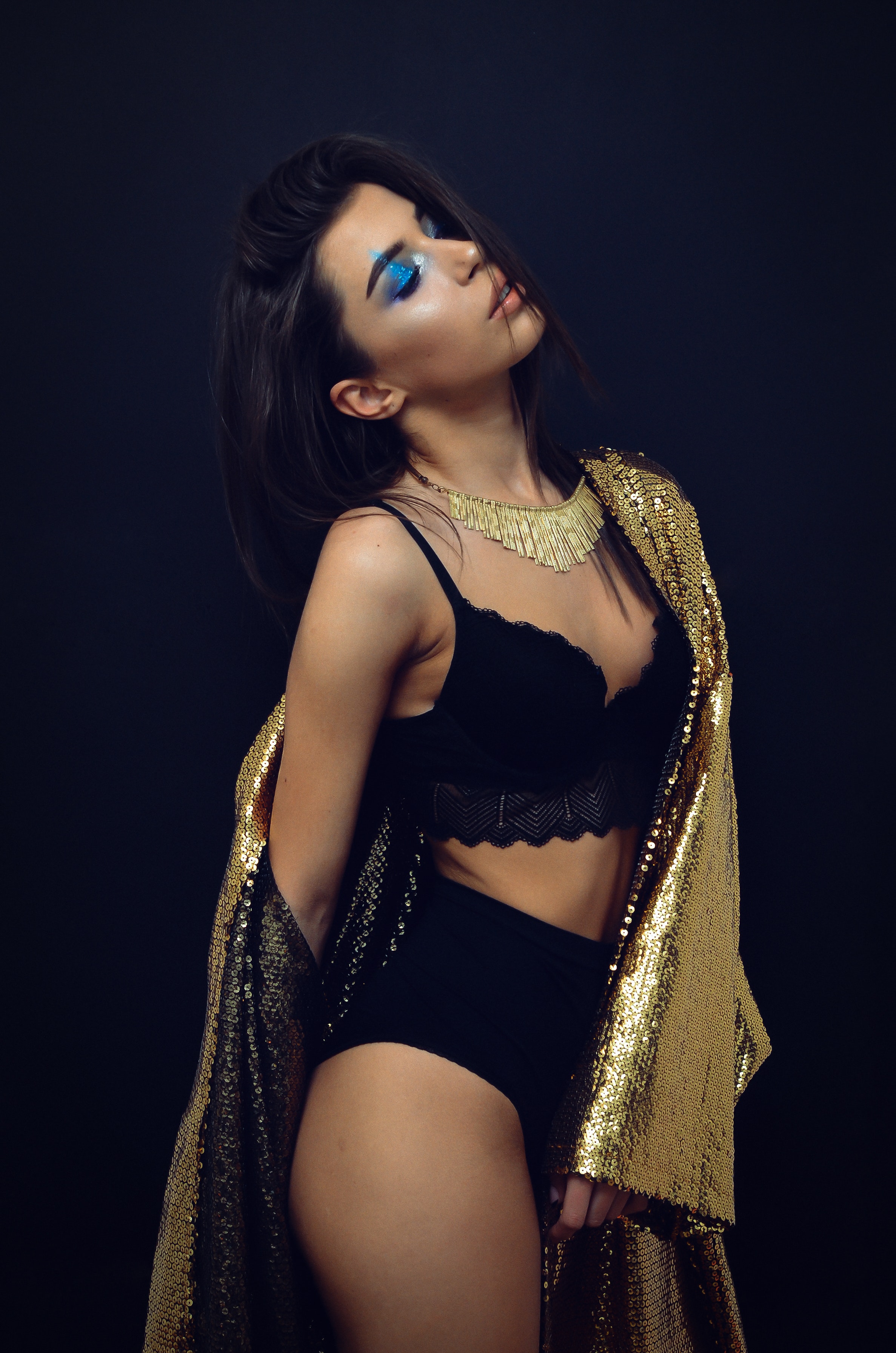 Woman wearing black brassiere and panty with sequinned gold-colored coat robe photo