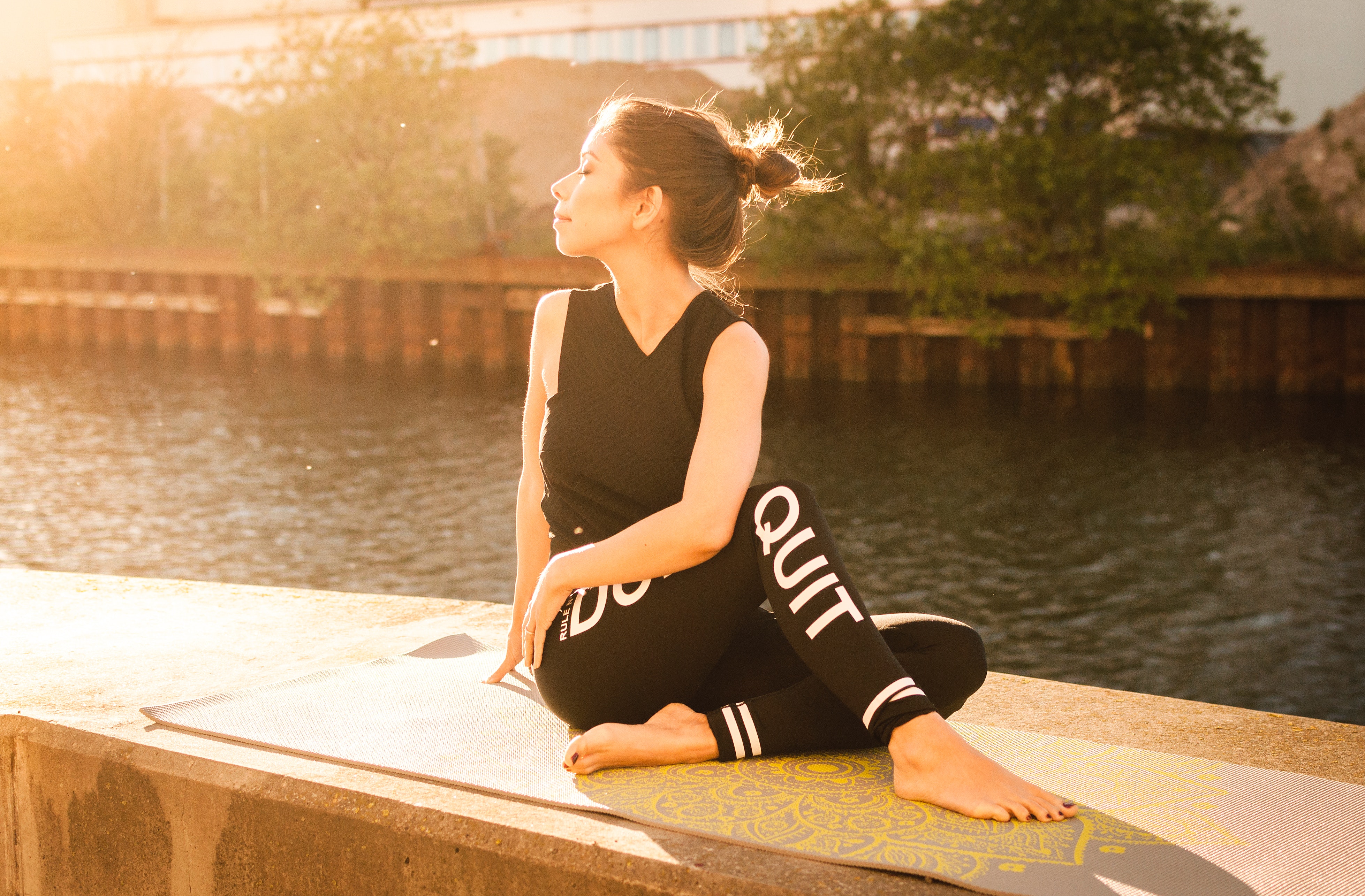 Woman wearing black fitness outfit performs yoga near body of water photo