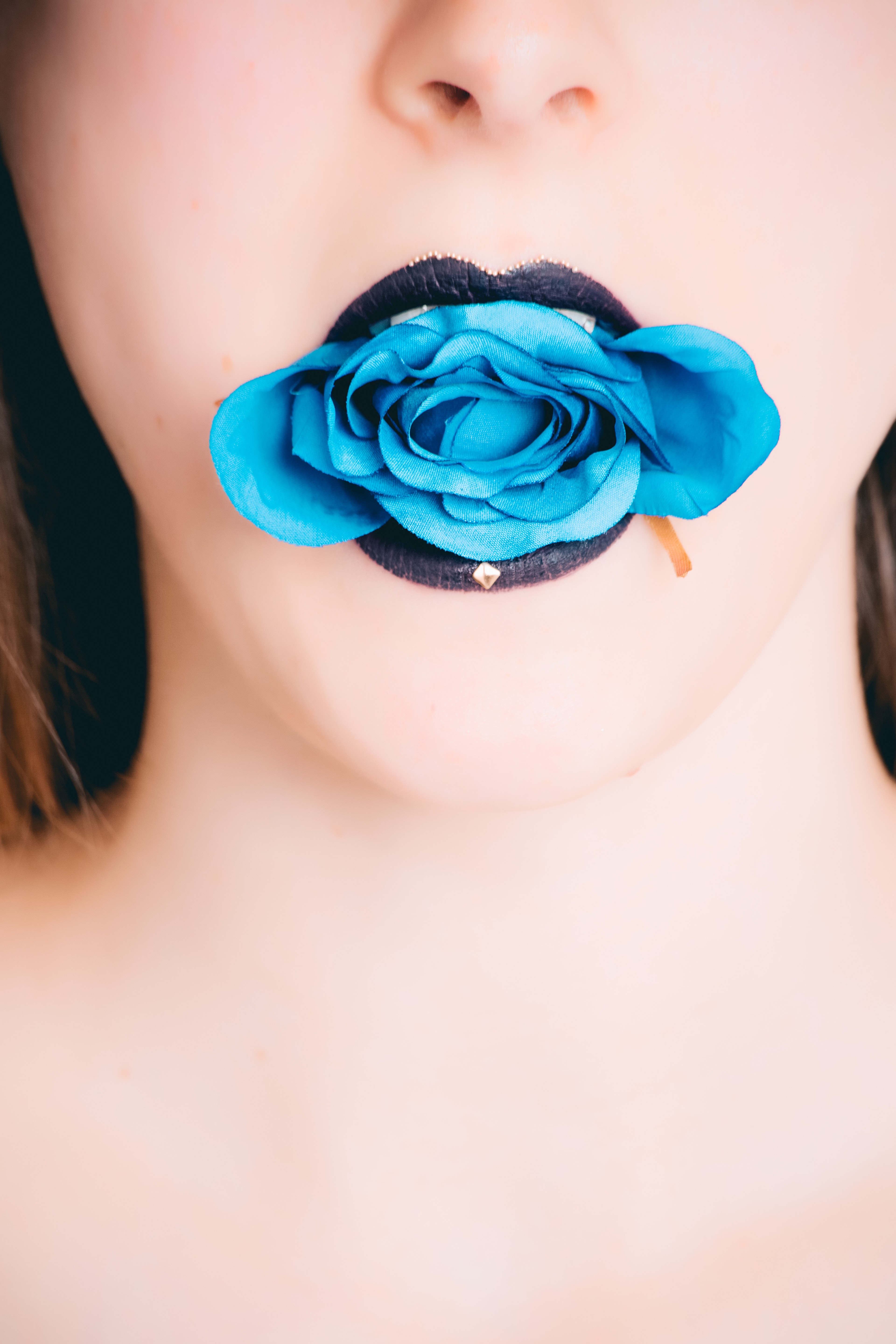 Woman wearing black lipstick with blue rose on mouth photo
