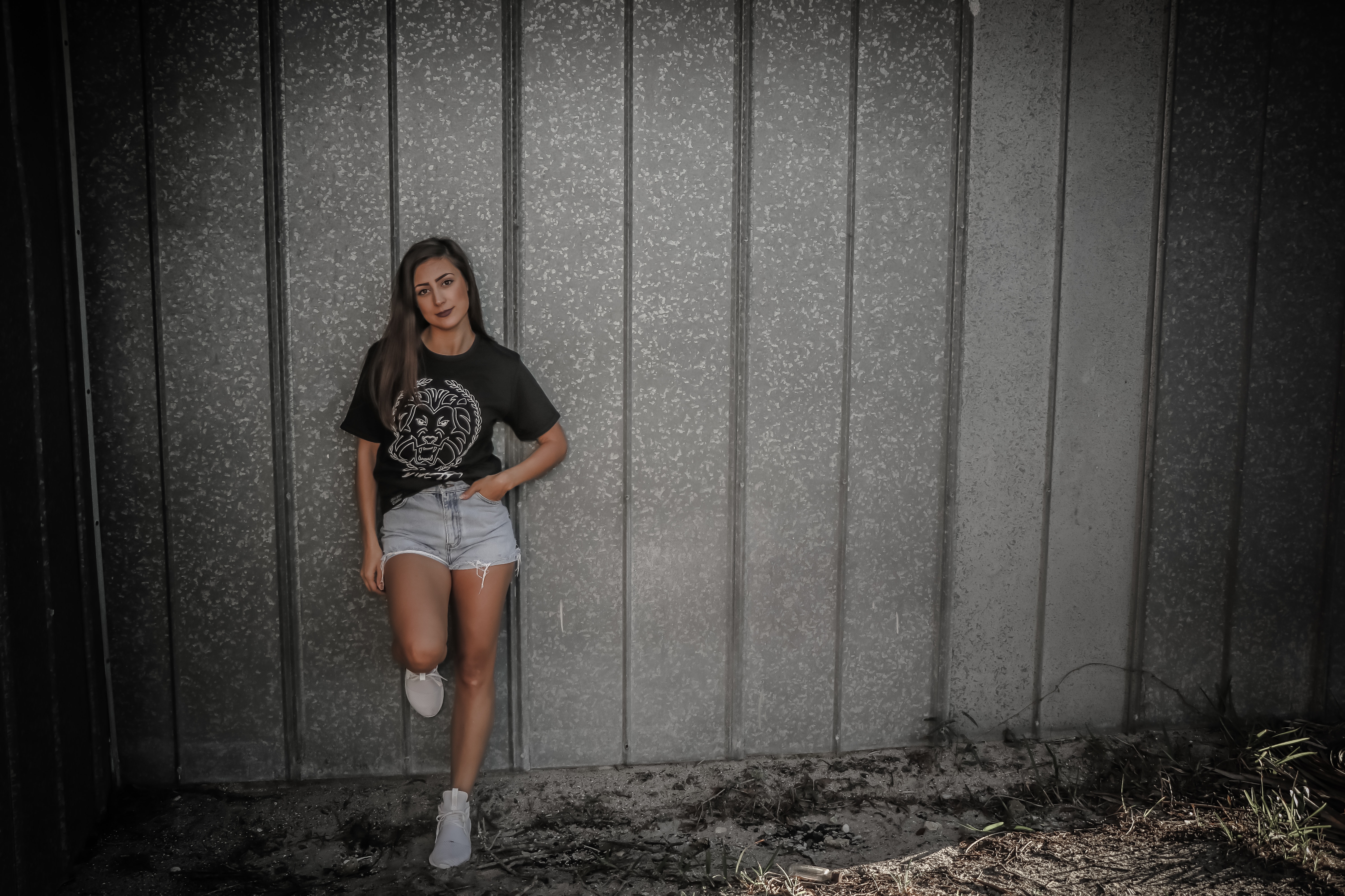 Woman wearing black shirt and daisy dukes leaning on wall photo