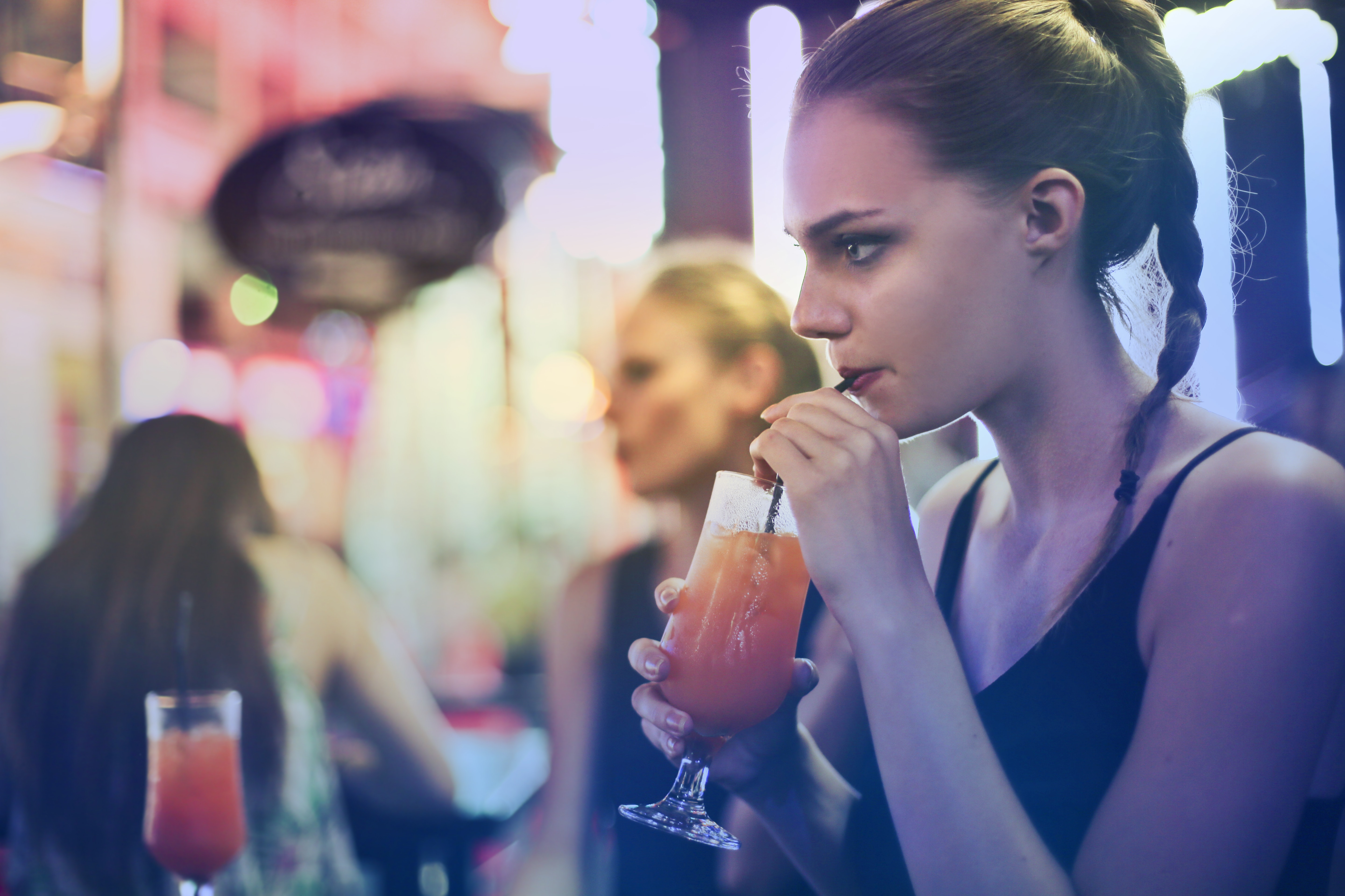 Woman wearing black spaghetti strap top and sipping drink photo