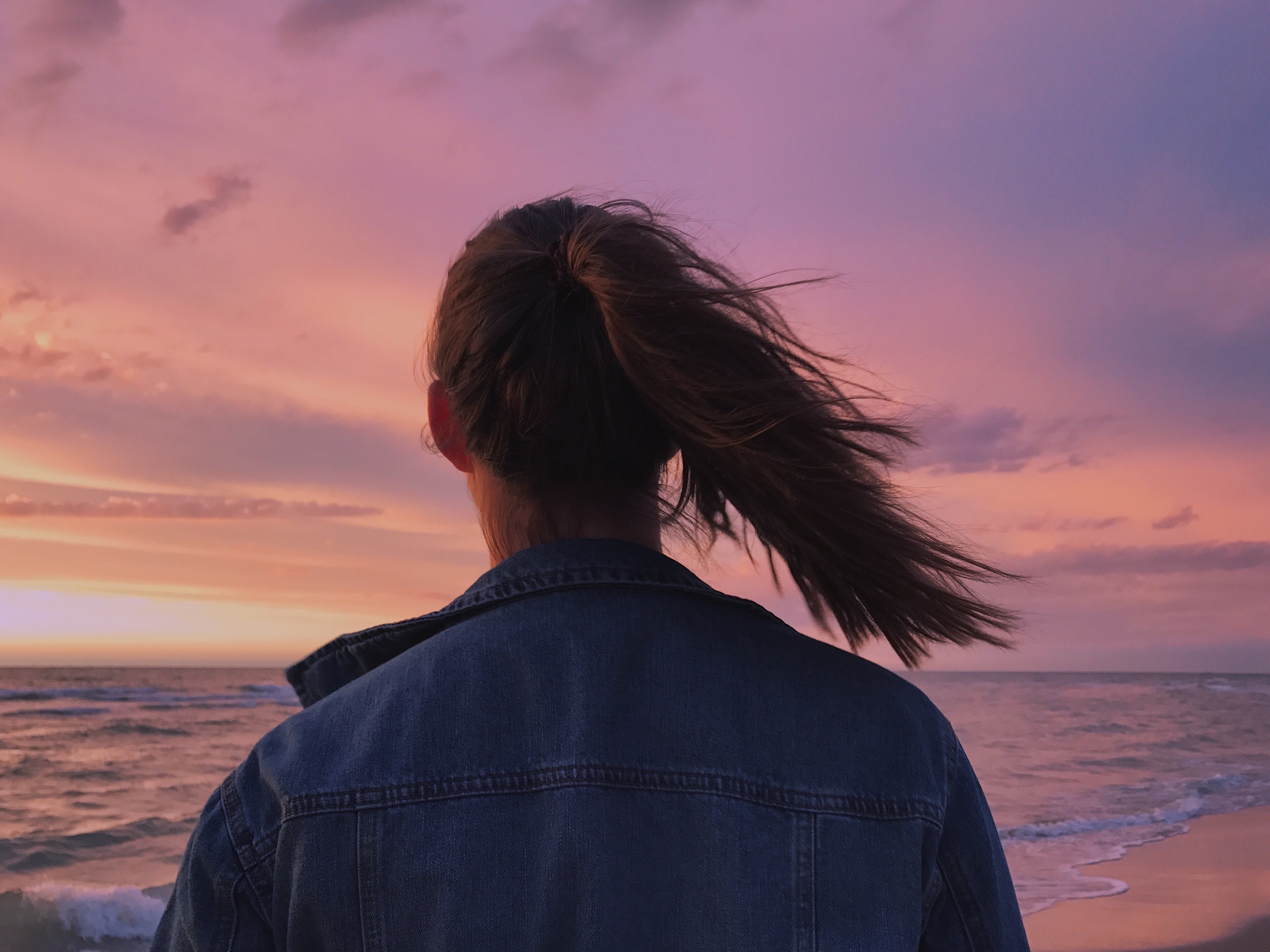 Woman wearing blue denim jacket looking at the beach photo