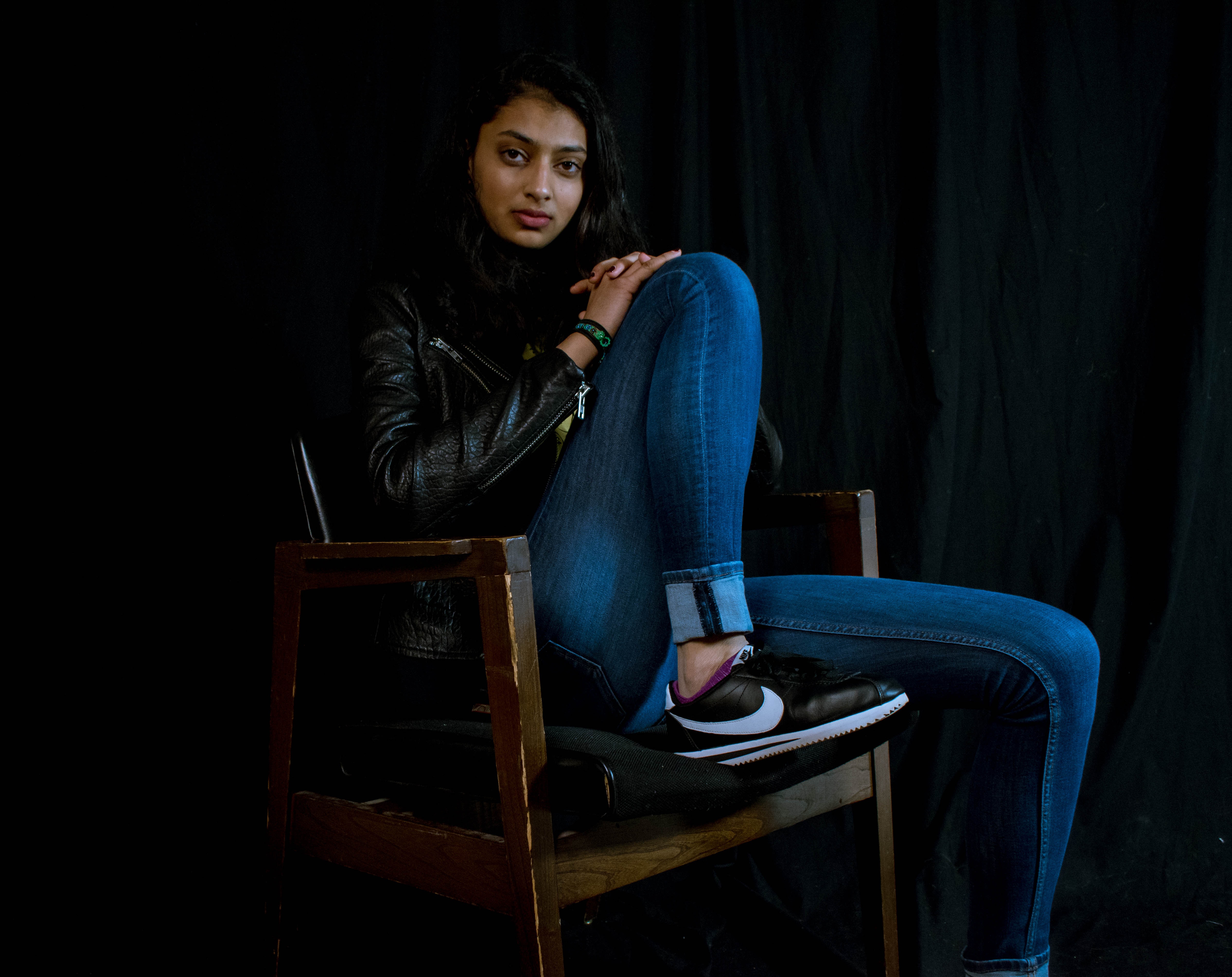 Woman wearing blue jeans sitting on brown wooden armchair photo