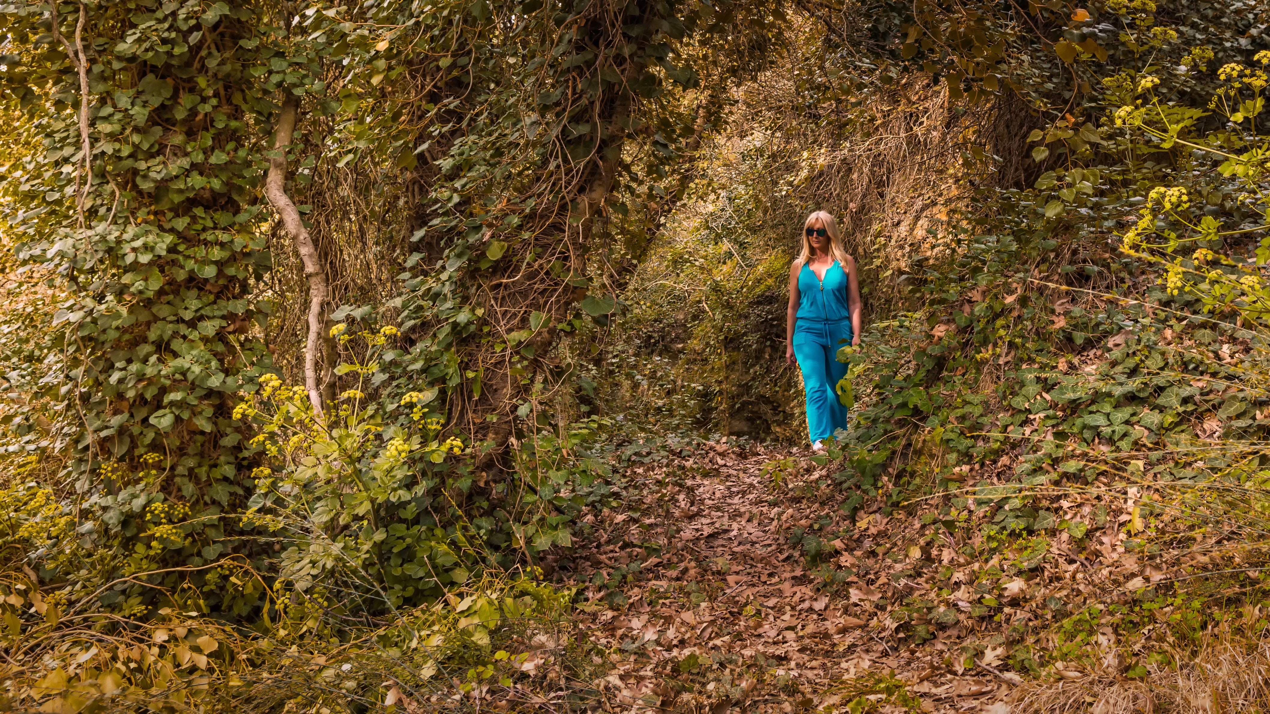 Woman wearing blue jumpsuit walking in forest photo