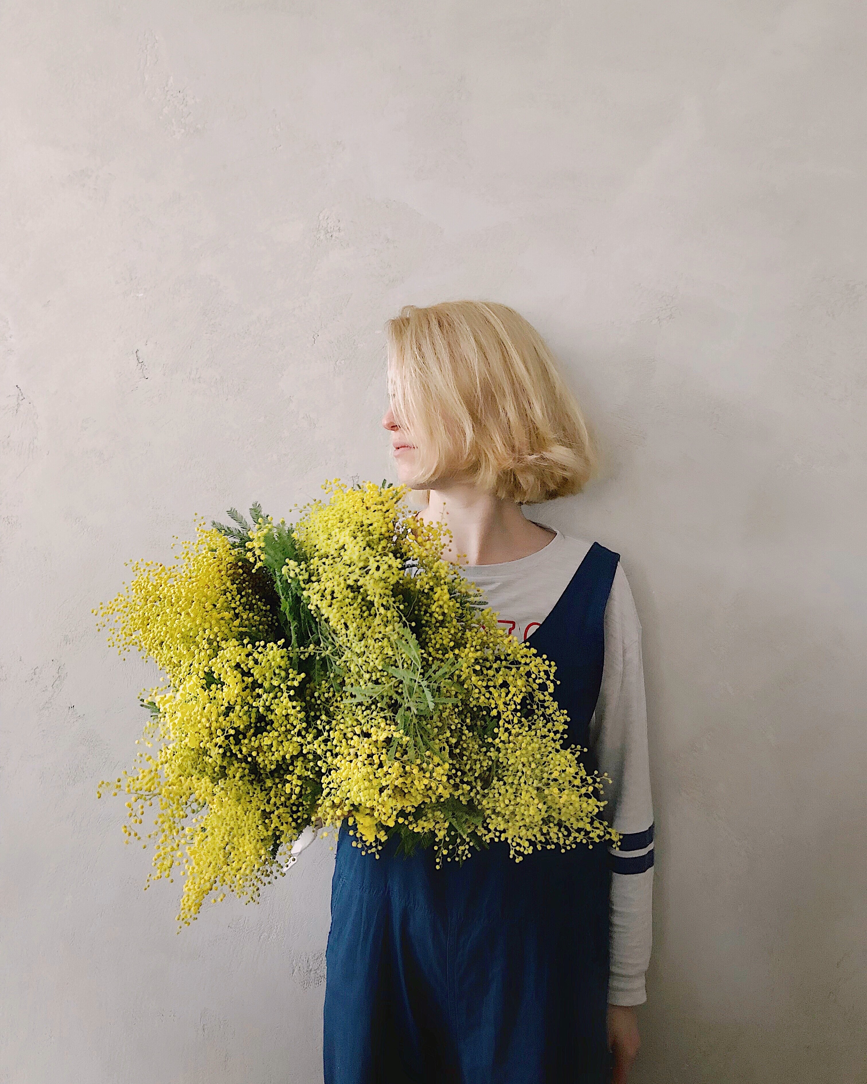 Woman wearing blue v-neck sleeveless top while holding yellow petaled flower photo