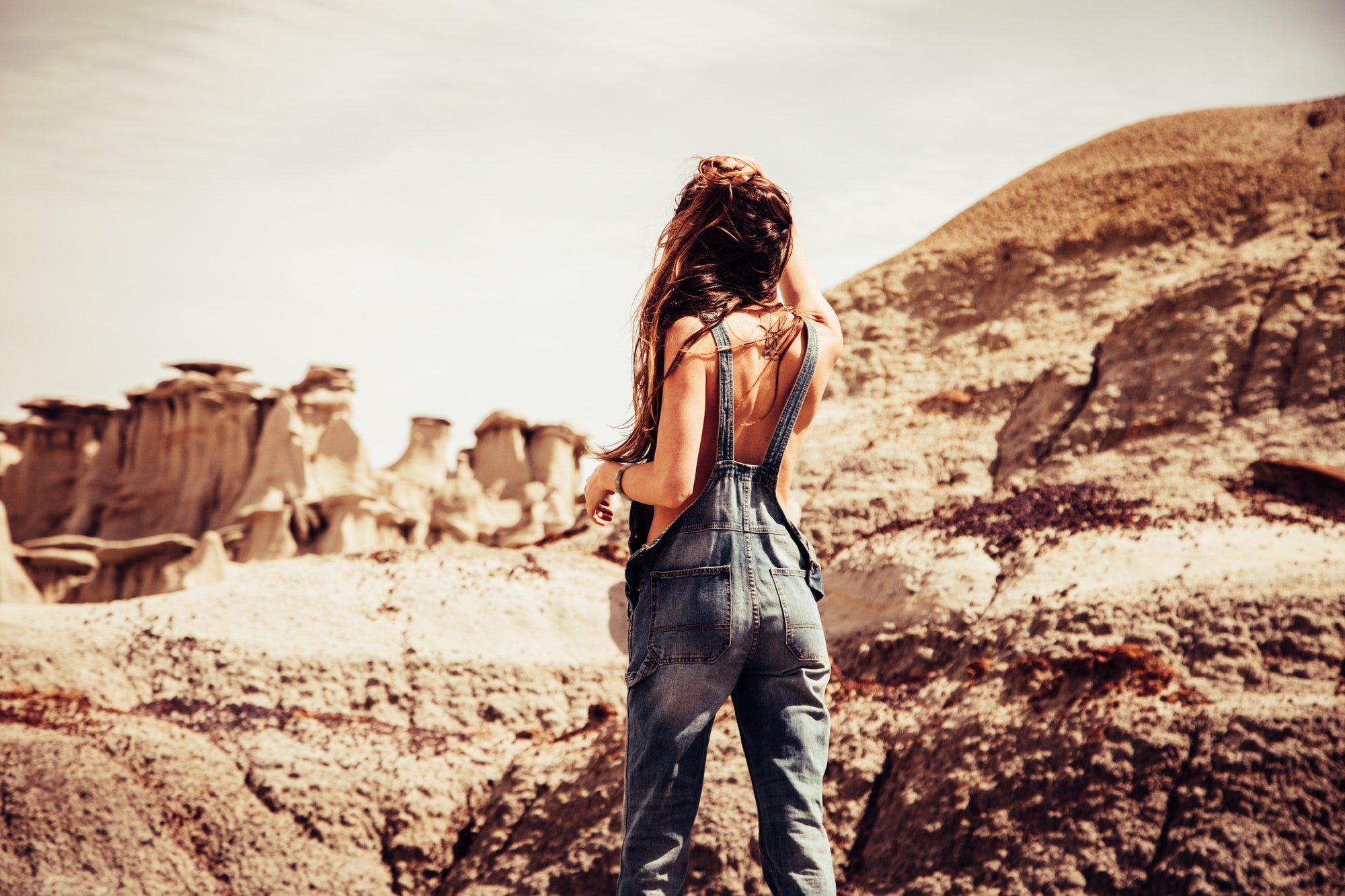 Woman wearing blue-washed overalls near rock formation photo