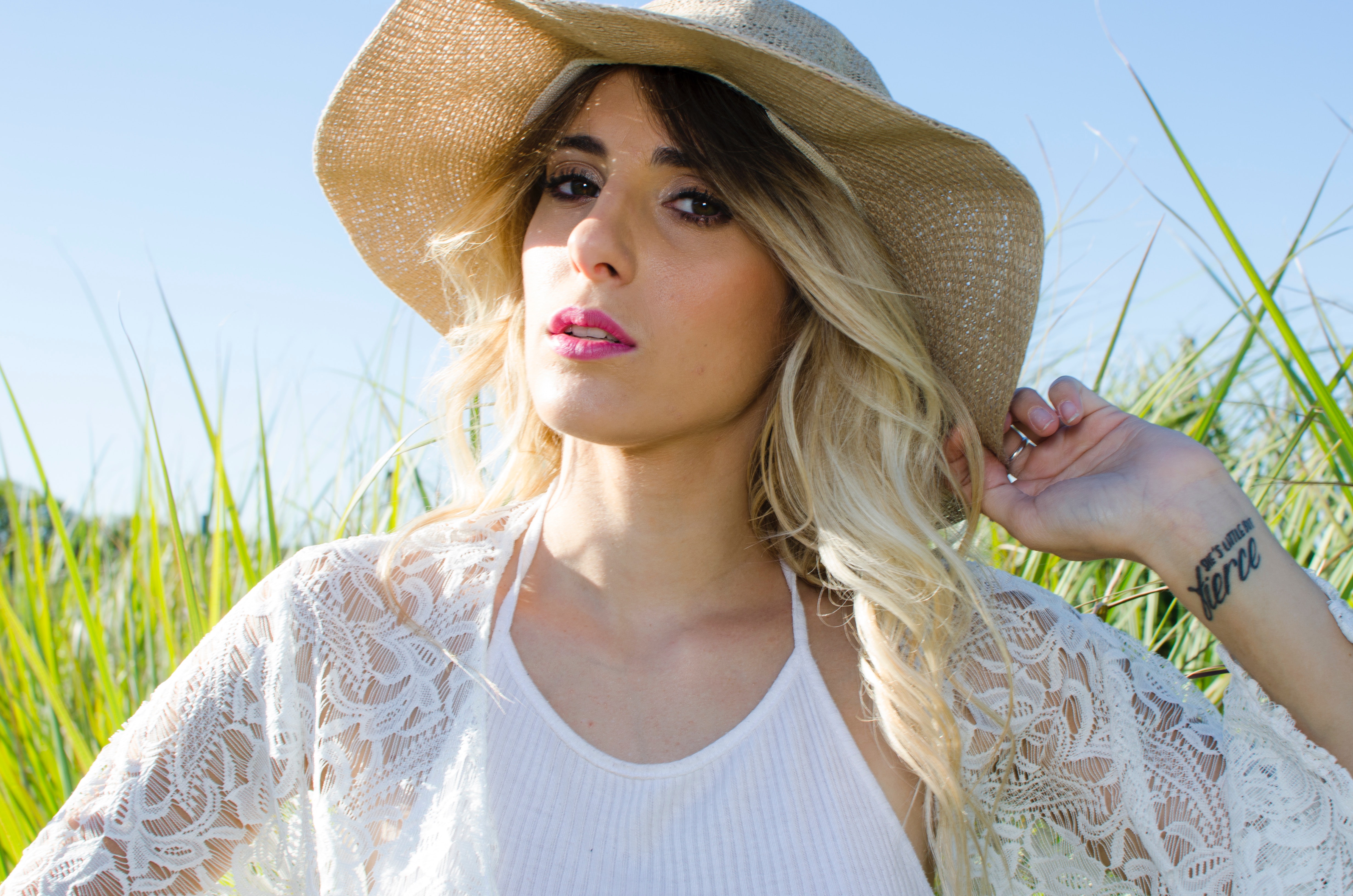 Woman wearing brown hat and white cardigan standing in middle of grass field photo
