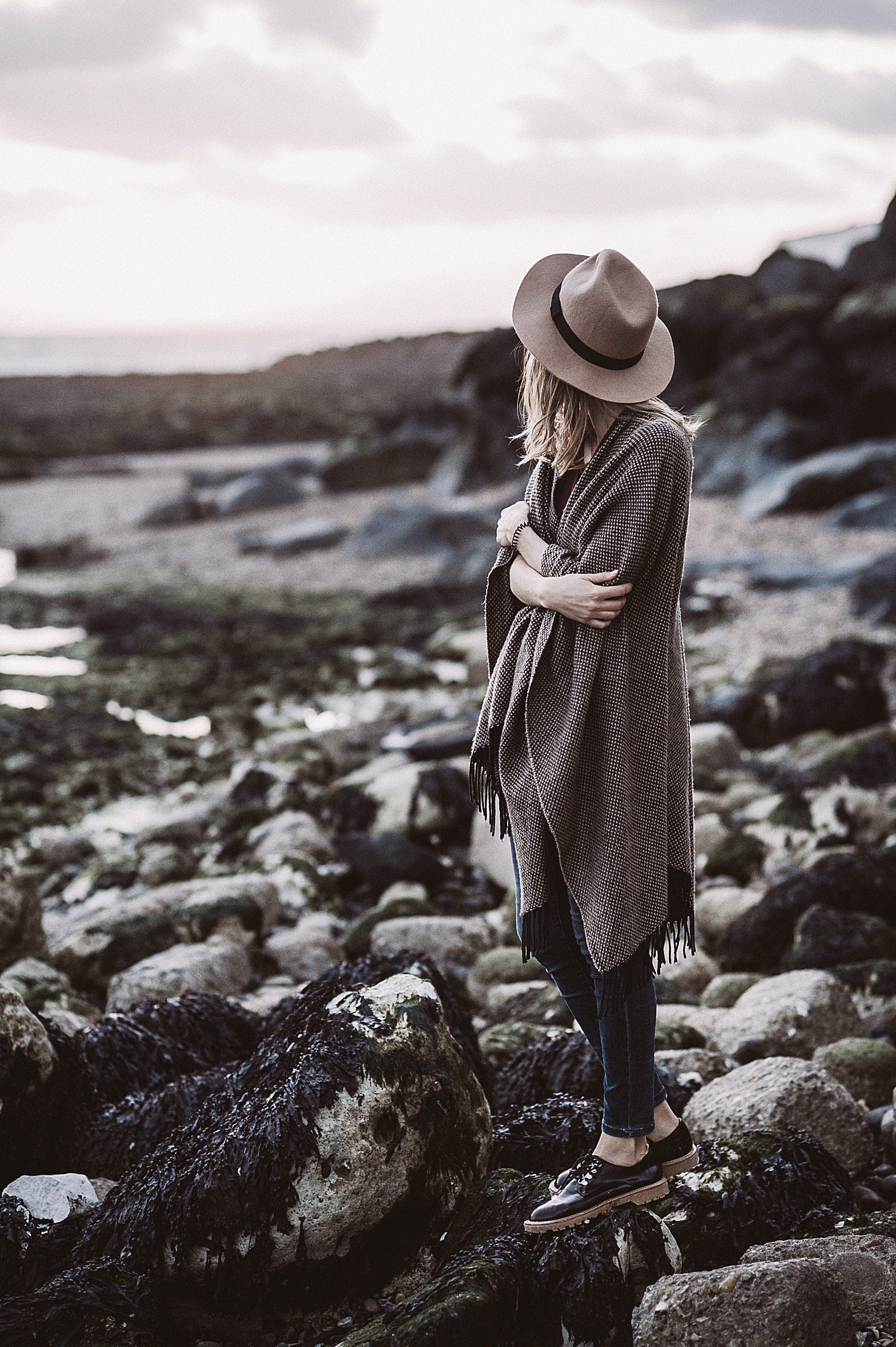 Woman wearing draped coat standing on rock facing mountain photo