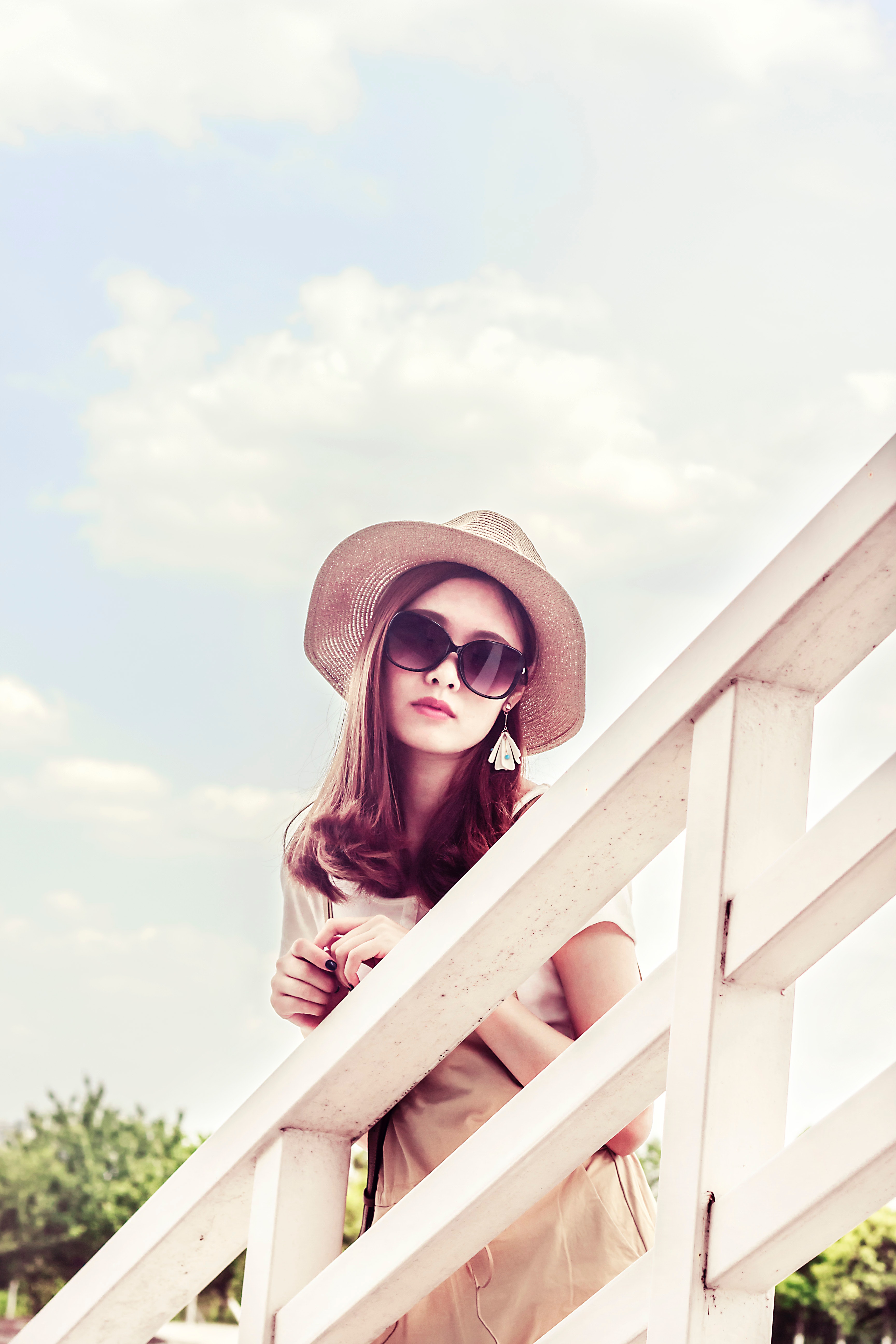 Woman wearing gray sun hat in front of white fence photo