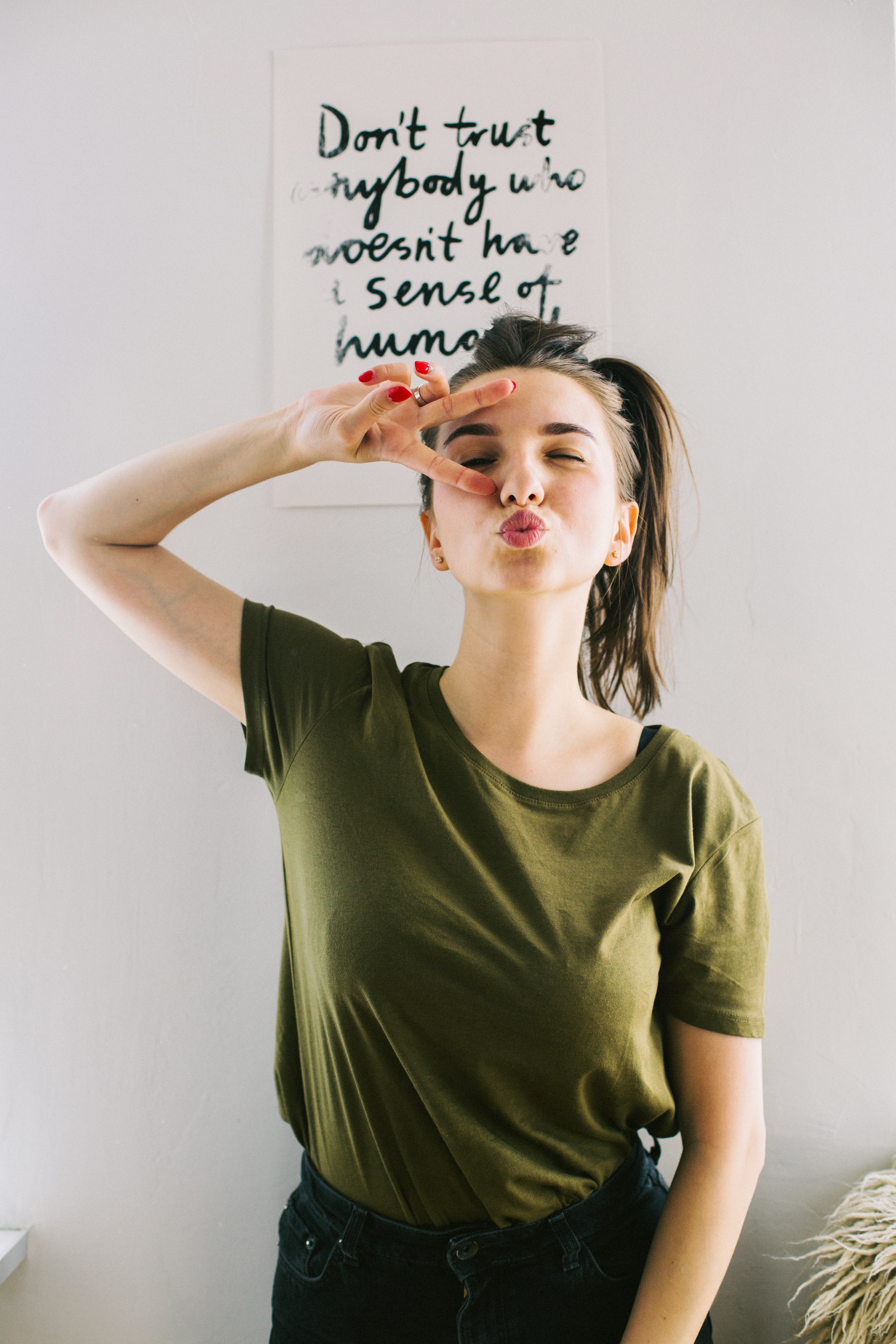 Woman Wearing Green Crew-neck T-shirt and Black Denim Bottoms Making Face Behind Don't Trust Anybody Who Doesn't Have a Sense of Humor Quote on White Wall, Adolescent, Looking, Woman, Wear, HQ Photo