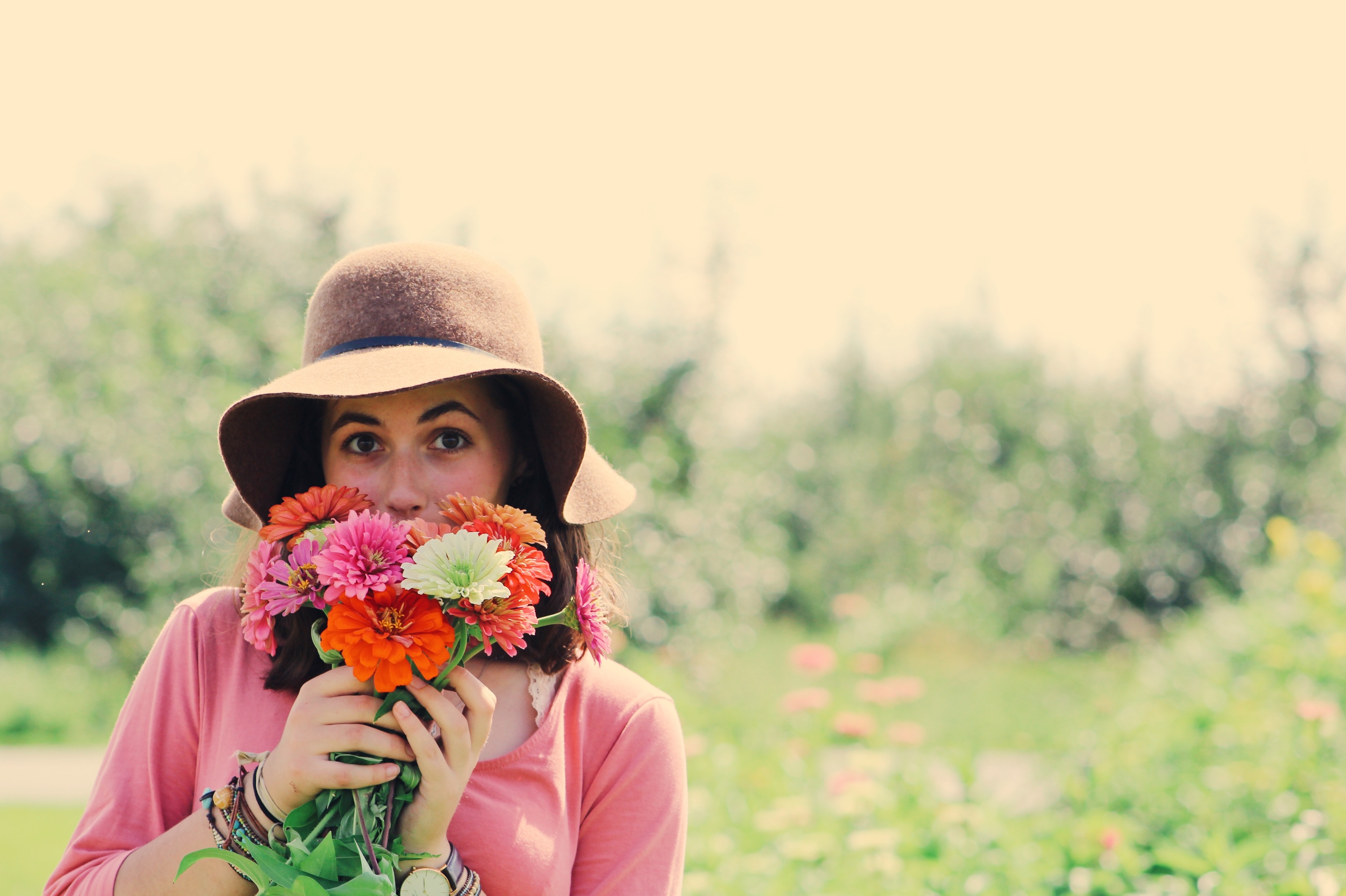 Woman wearing hat and holding flowers surrounded by plants photo