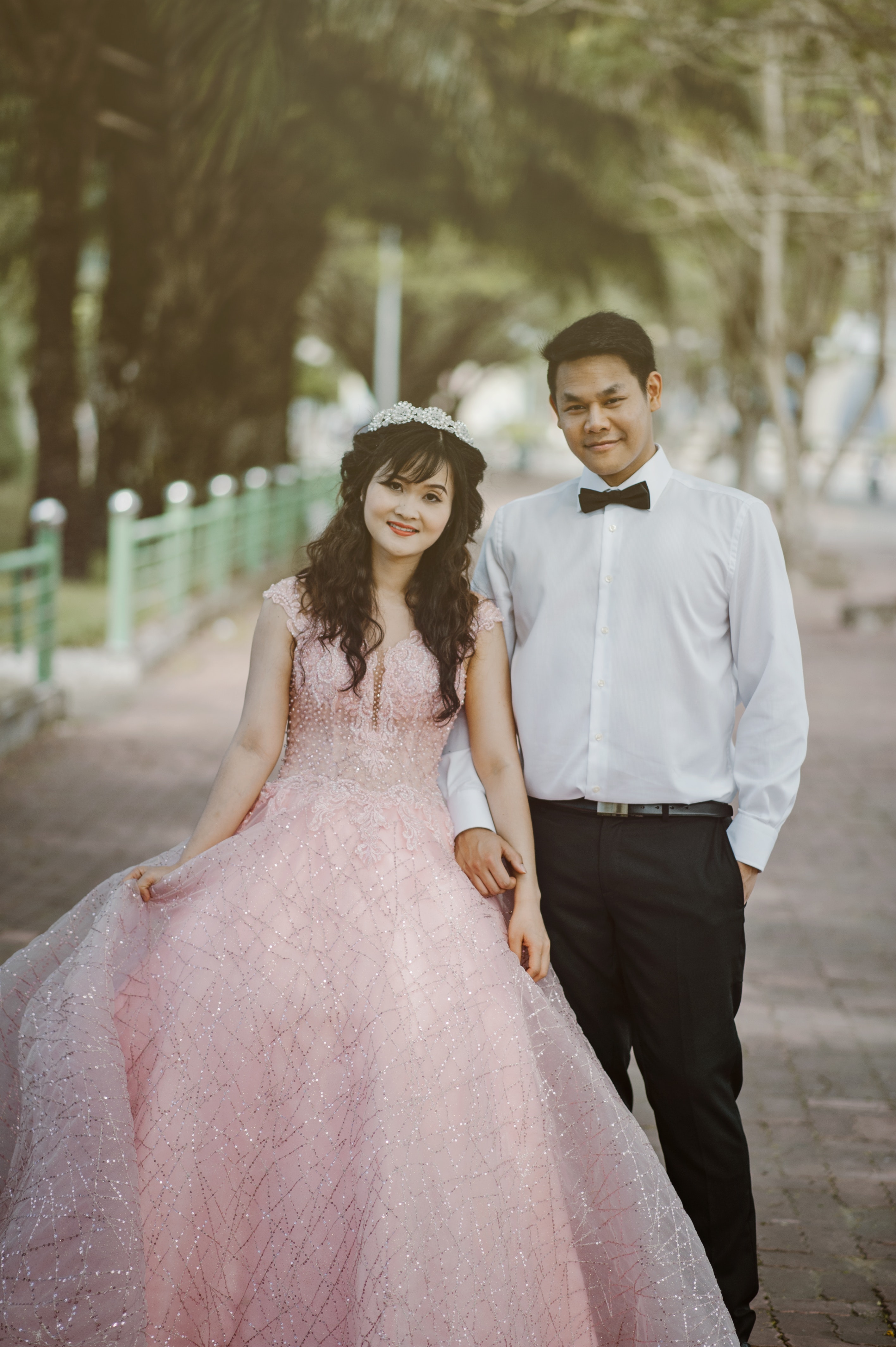 Woman wearing pink wedding gown standing next to man wearing white dress shirt photo