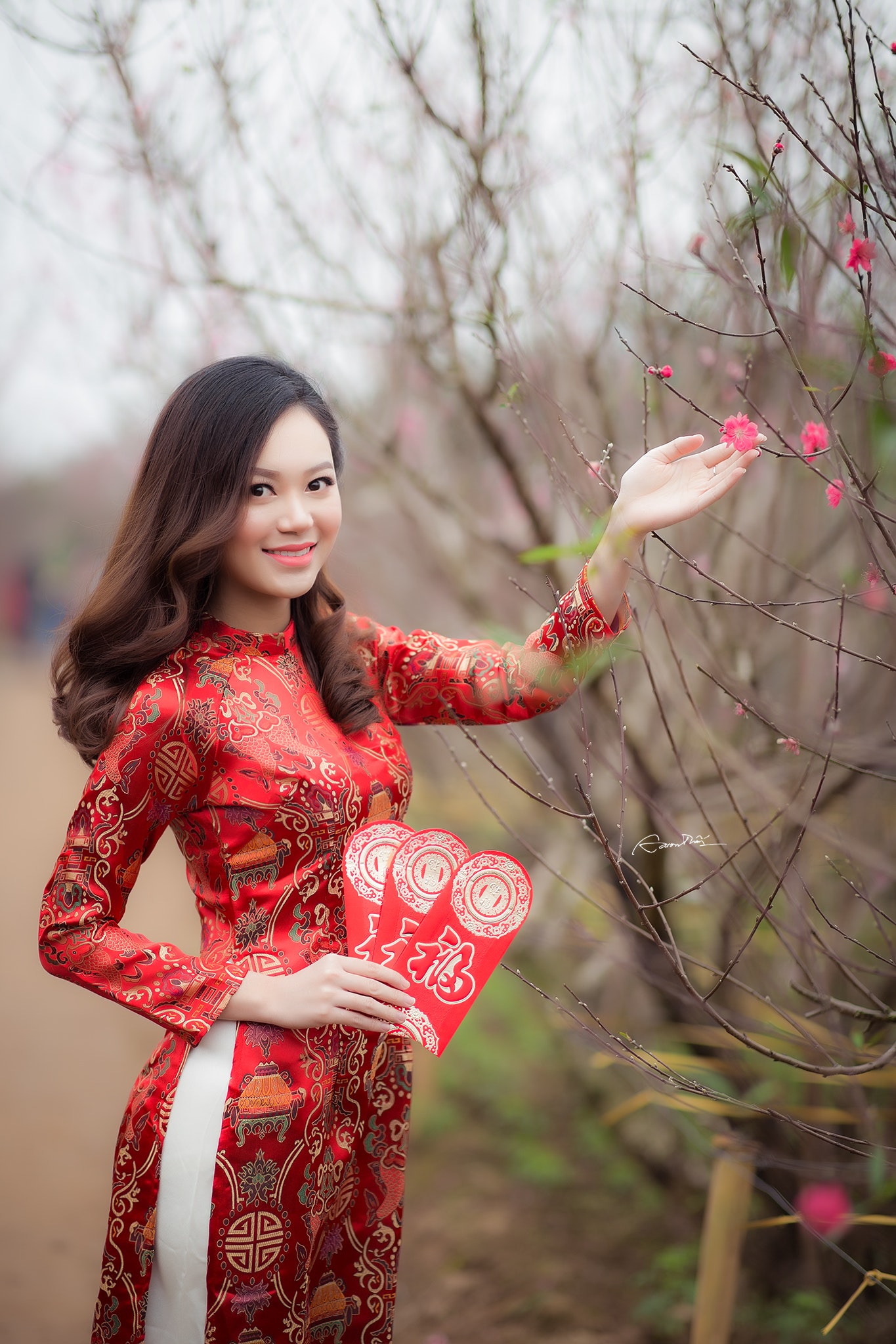 Woman wearing red long-sleeved dress holding pink petaled flower photo