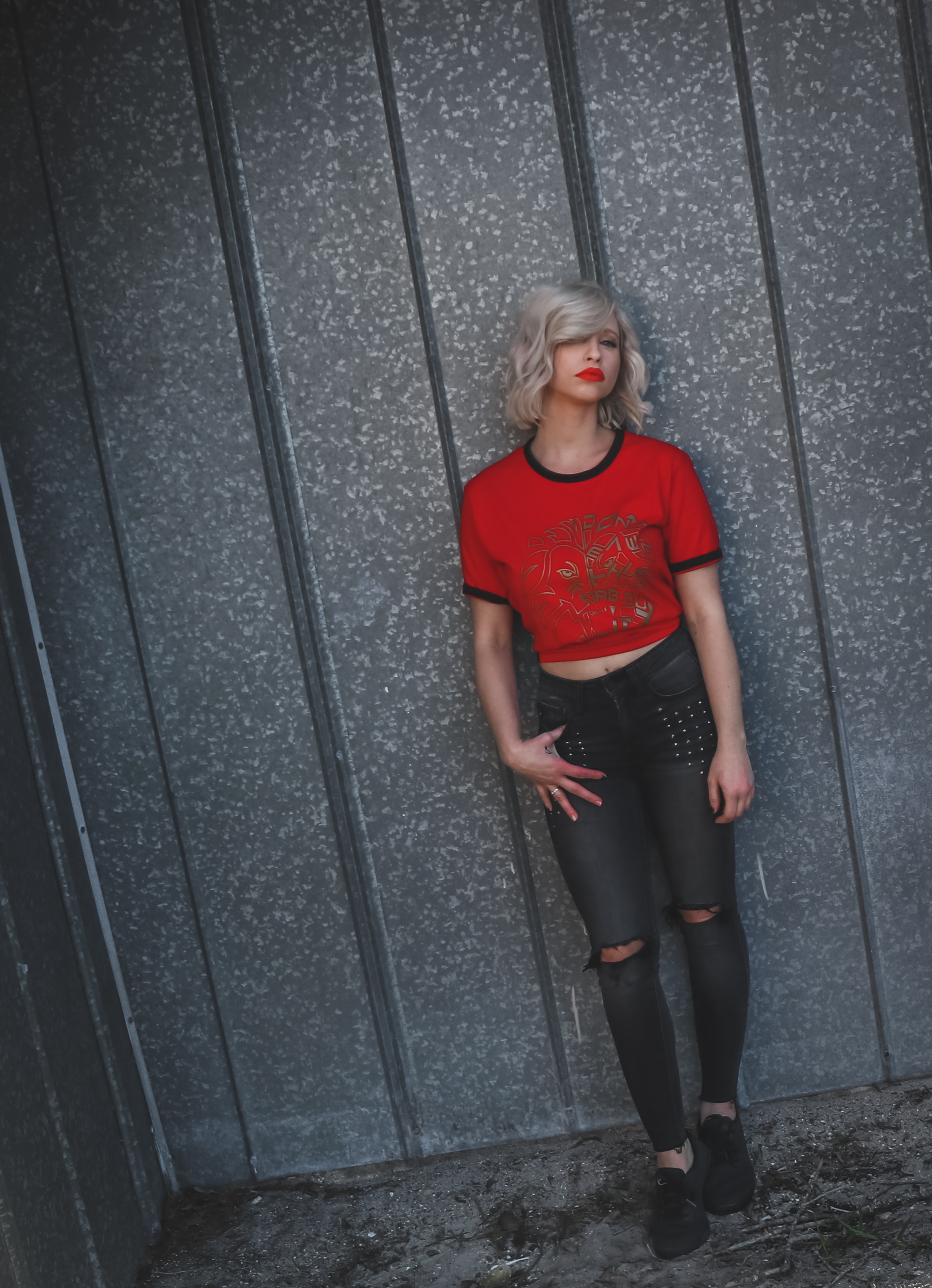 Woman wearing red shirt leaning on gray wall photo