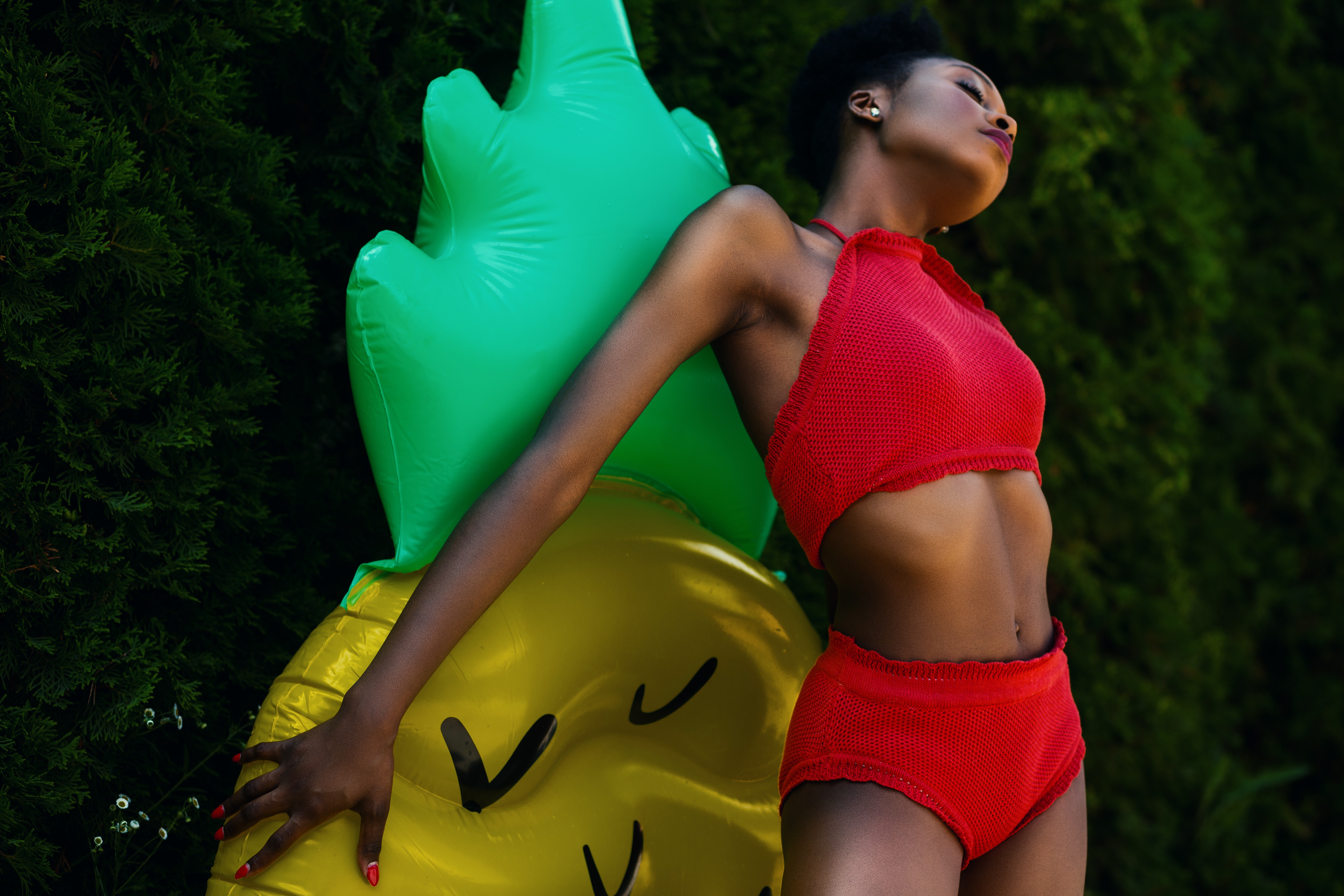 Woman wearing red top and bottoms leaning on yellow and green inflatable standee photo