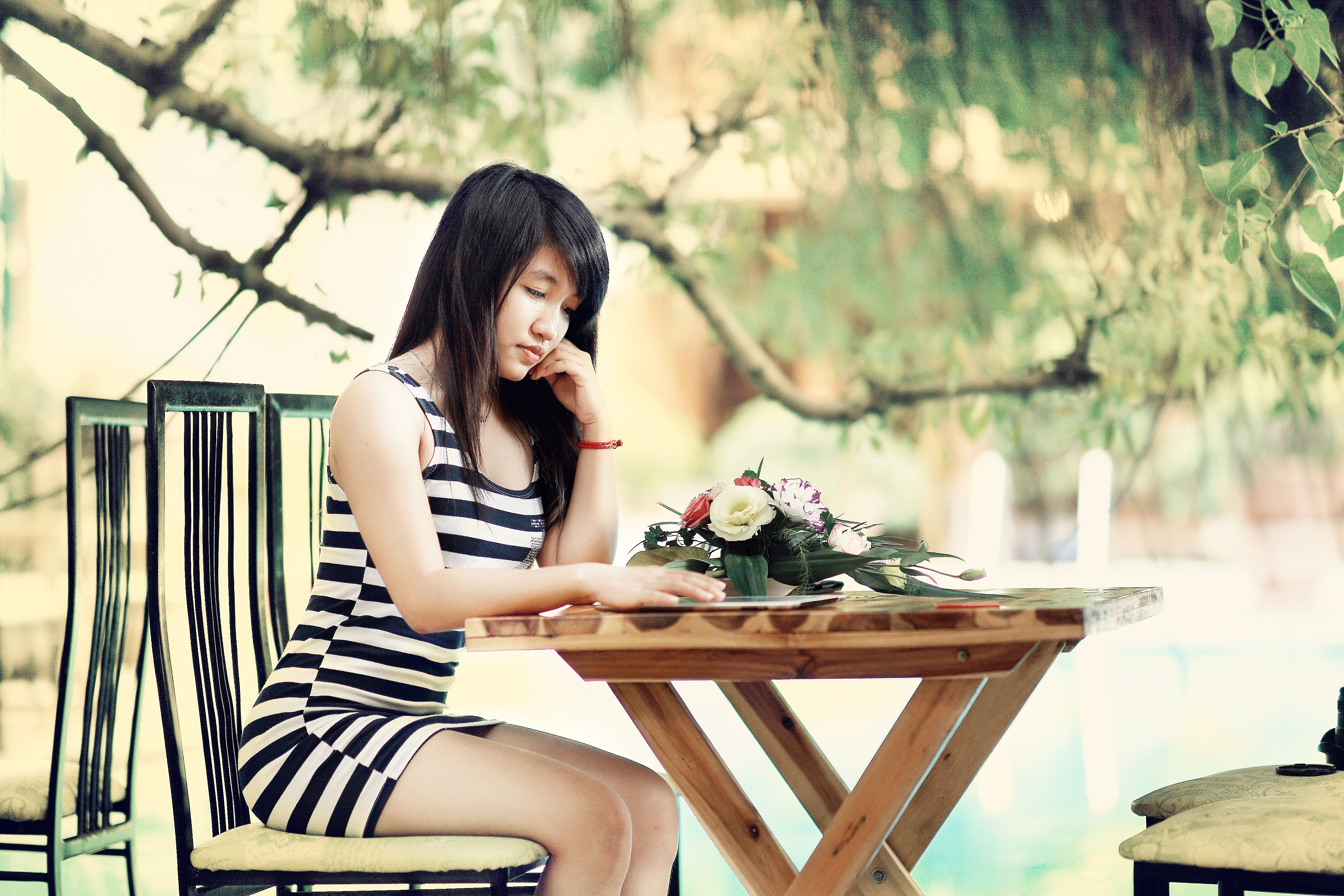 Woman wearing stripe tank bodycon dress sitting on chair leaning on table photo