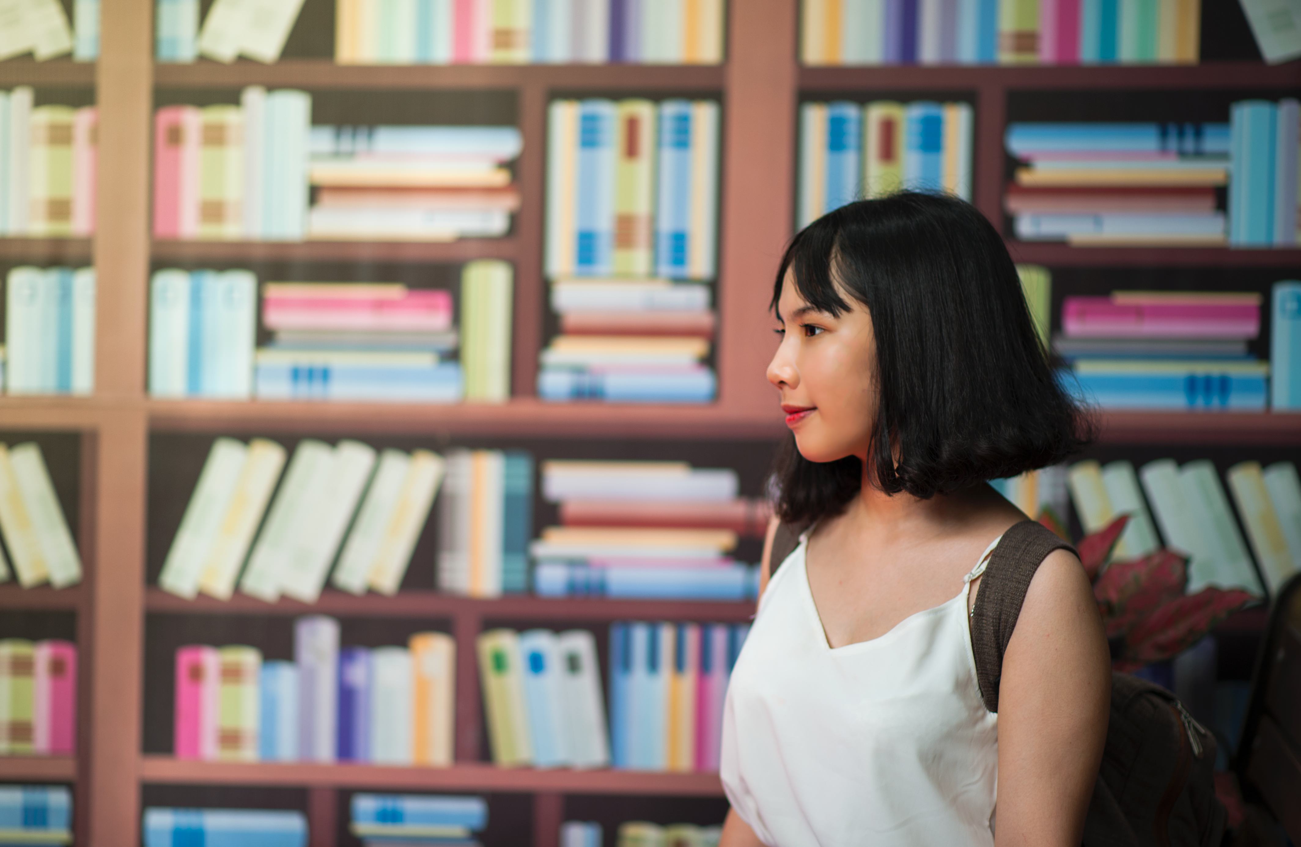 Woman wearing v-neck sleeveless top near bookshelf photo