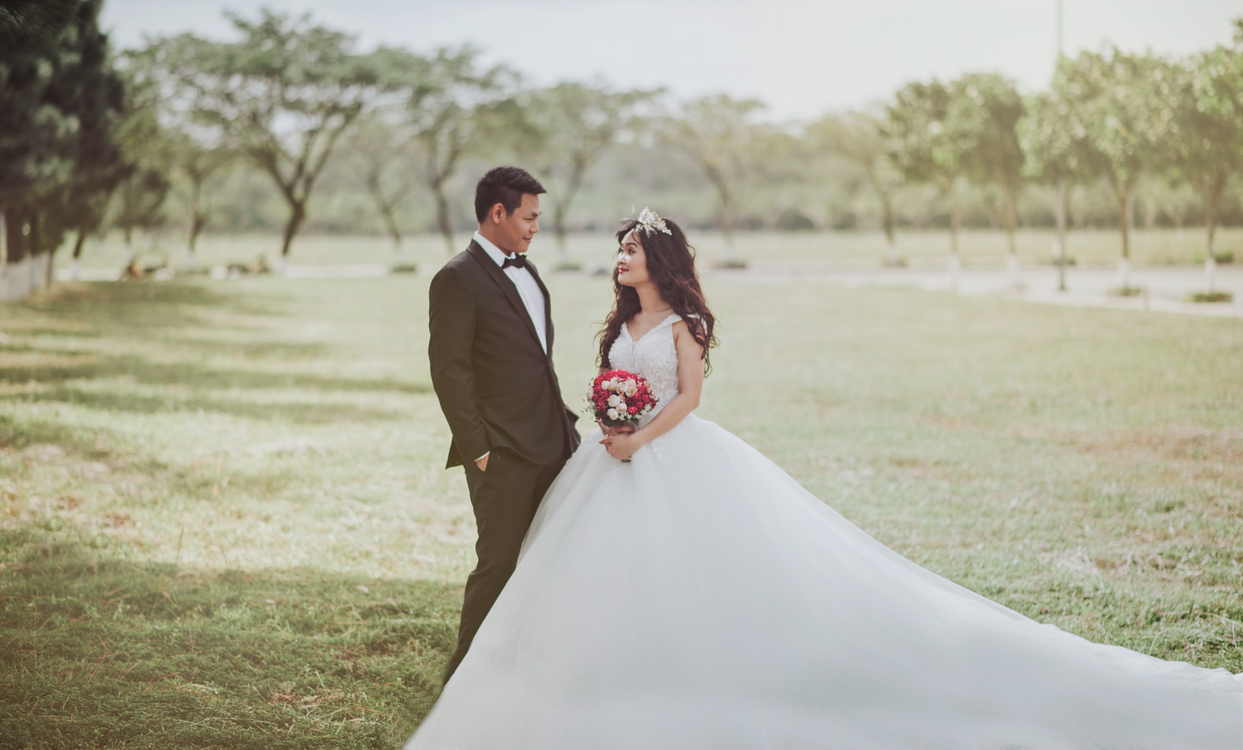 Woman wearing wedding dress standing beside a man wearing tuxedo photo