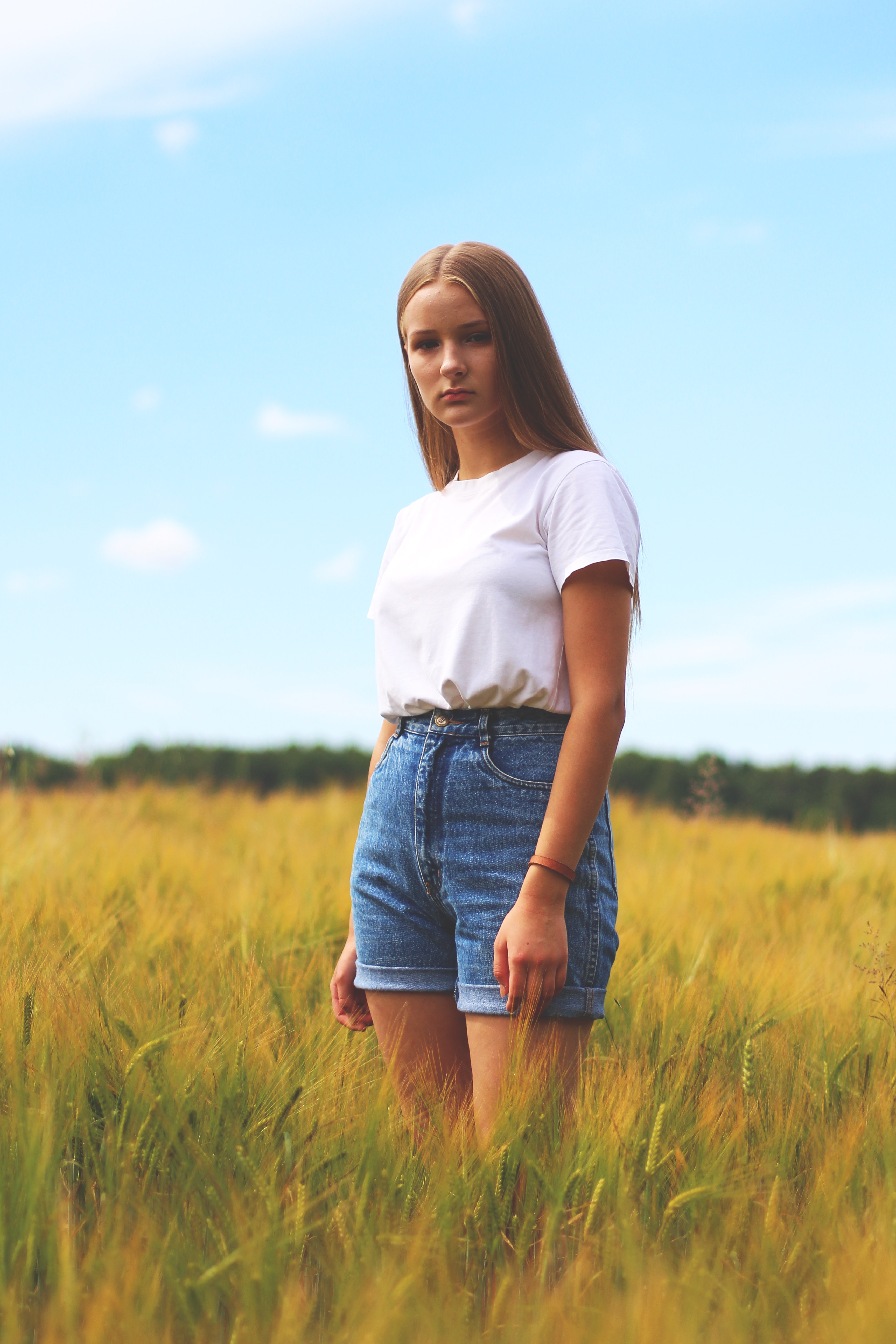 Woman Wearing White Crew-neck T-shirt, Blue Denim Cuff Short Shorts While Standing on Grass Field, Happy, Young, Woman, Trees, HQ Photo
