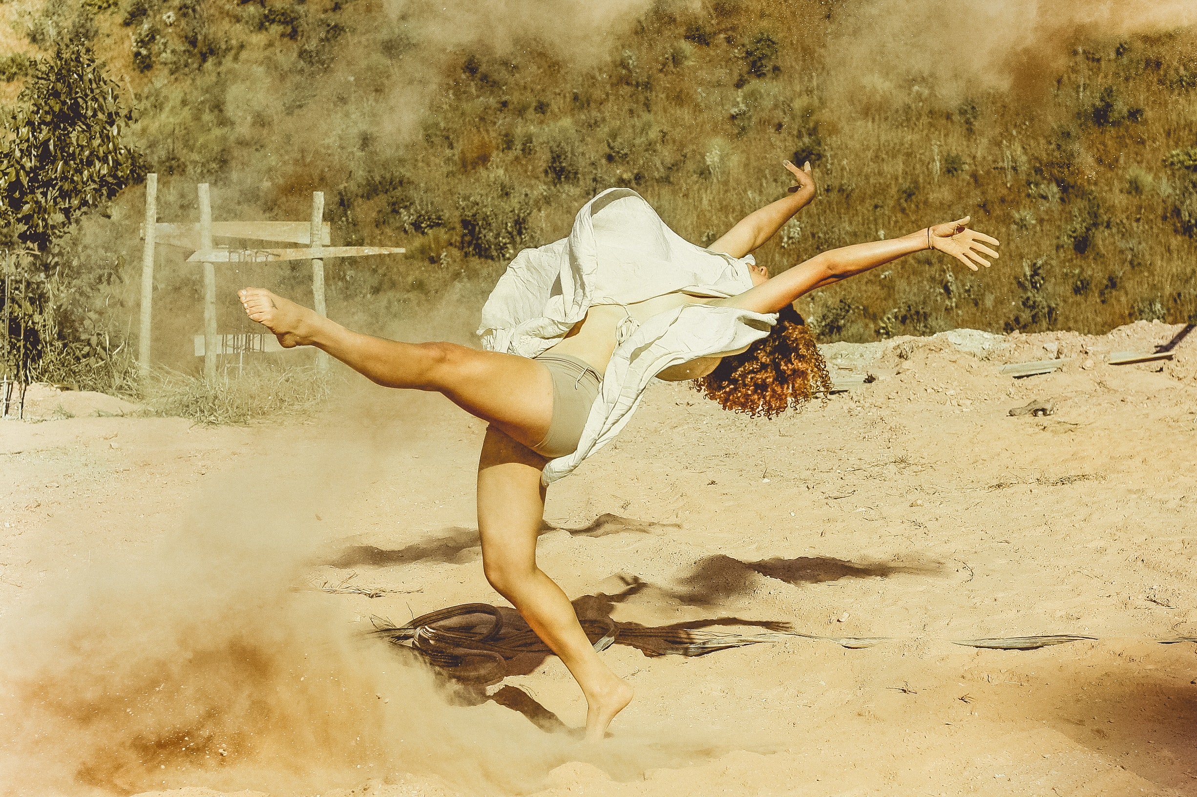Woman wearing white dress dancing on brown sand photo