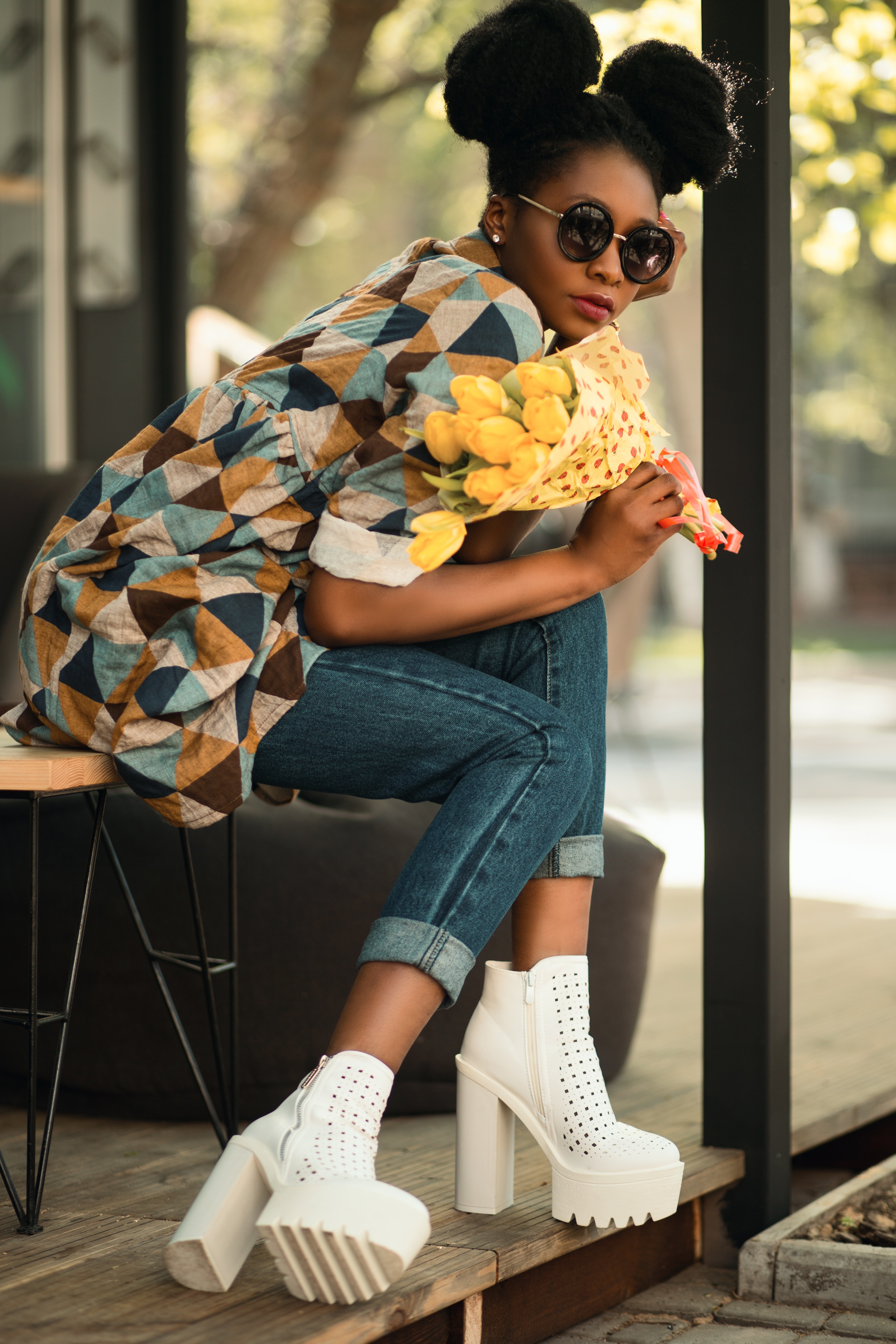 Woman wearing white-green-yellow geometric sleeved shirt, blue denim pants and white block heeled booties photo